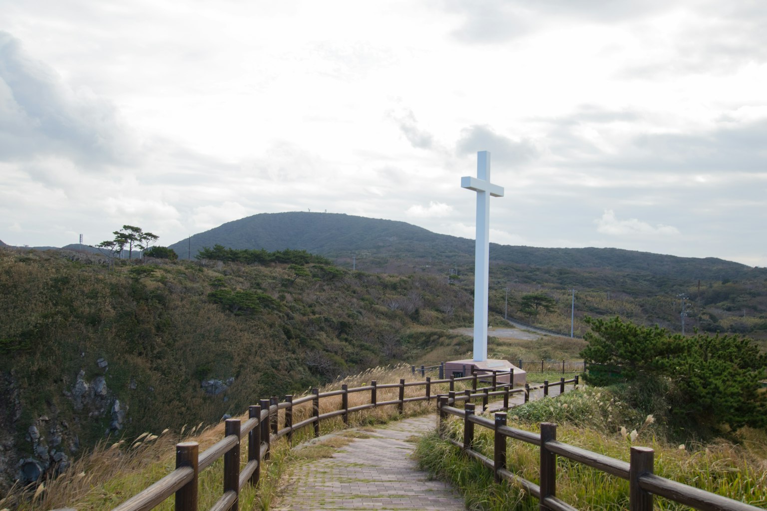 Un chemin pittoresque menant à une grande croix blanche surplombant des collines