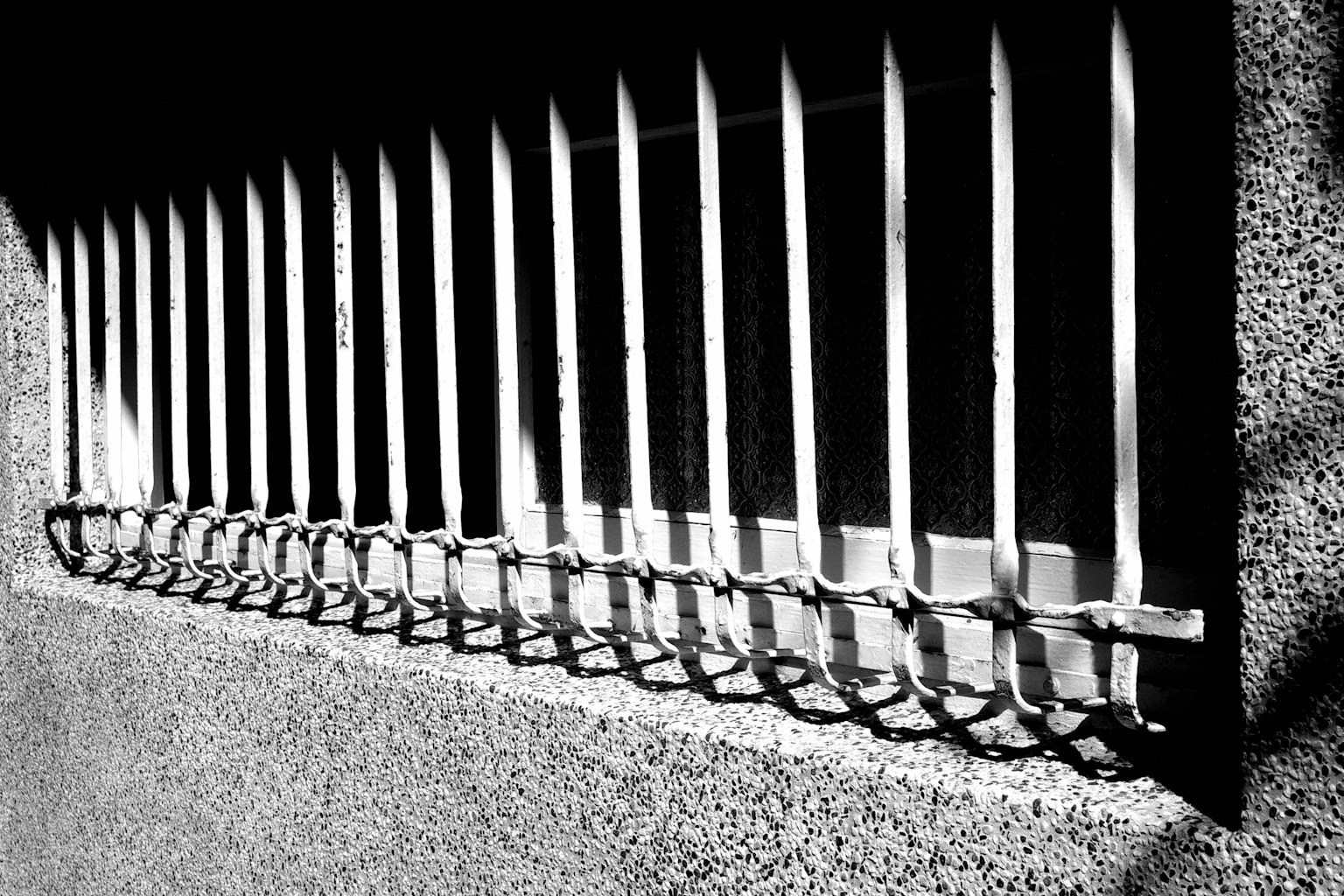 白黒の窓の格子と影のコントラストが際立つ画像