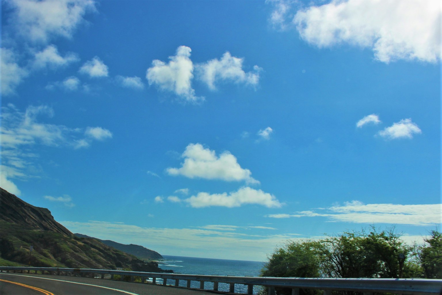 Carretera costera con cielo azul y nubes blancas