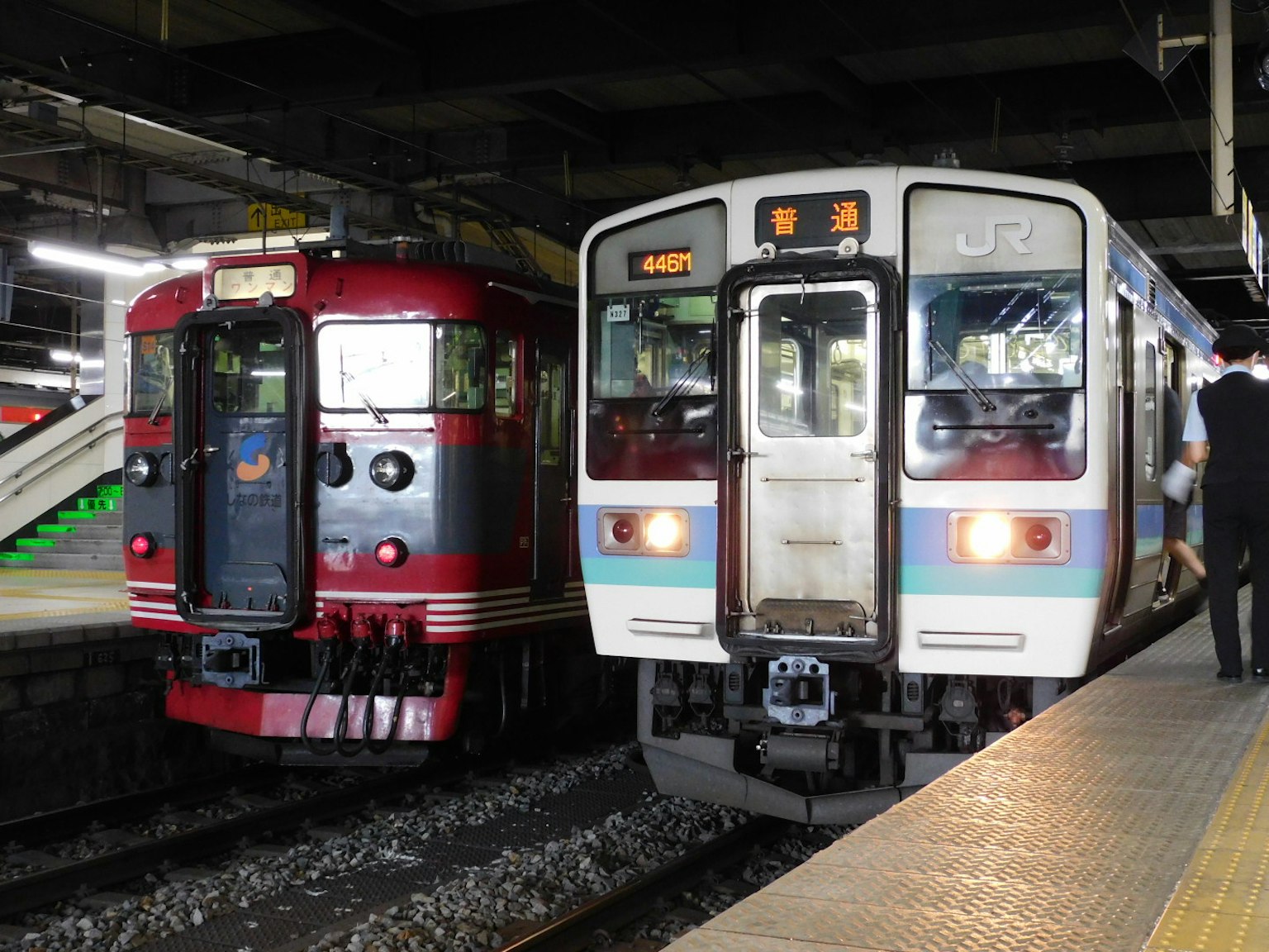รถไฟสีแดงและสีขาวอยู่ข้างกันที่สถานี
