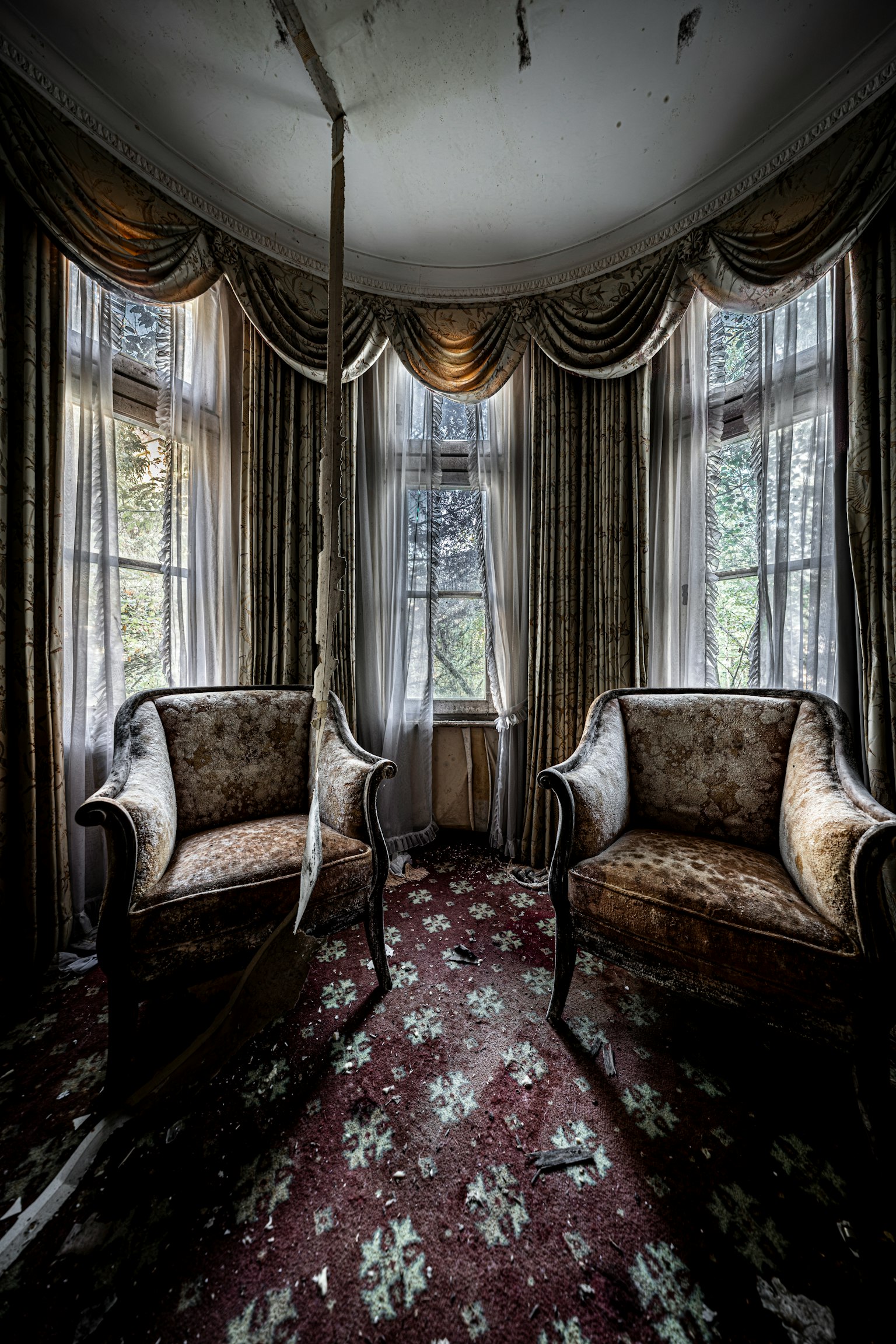 古い家具が置かれた部屋の内部　大きな窓から自然光が差し込む　豪華なカーテンと花柄のカーペット