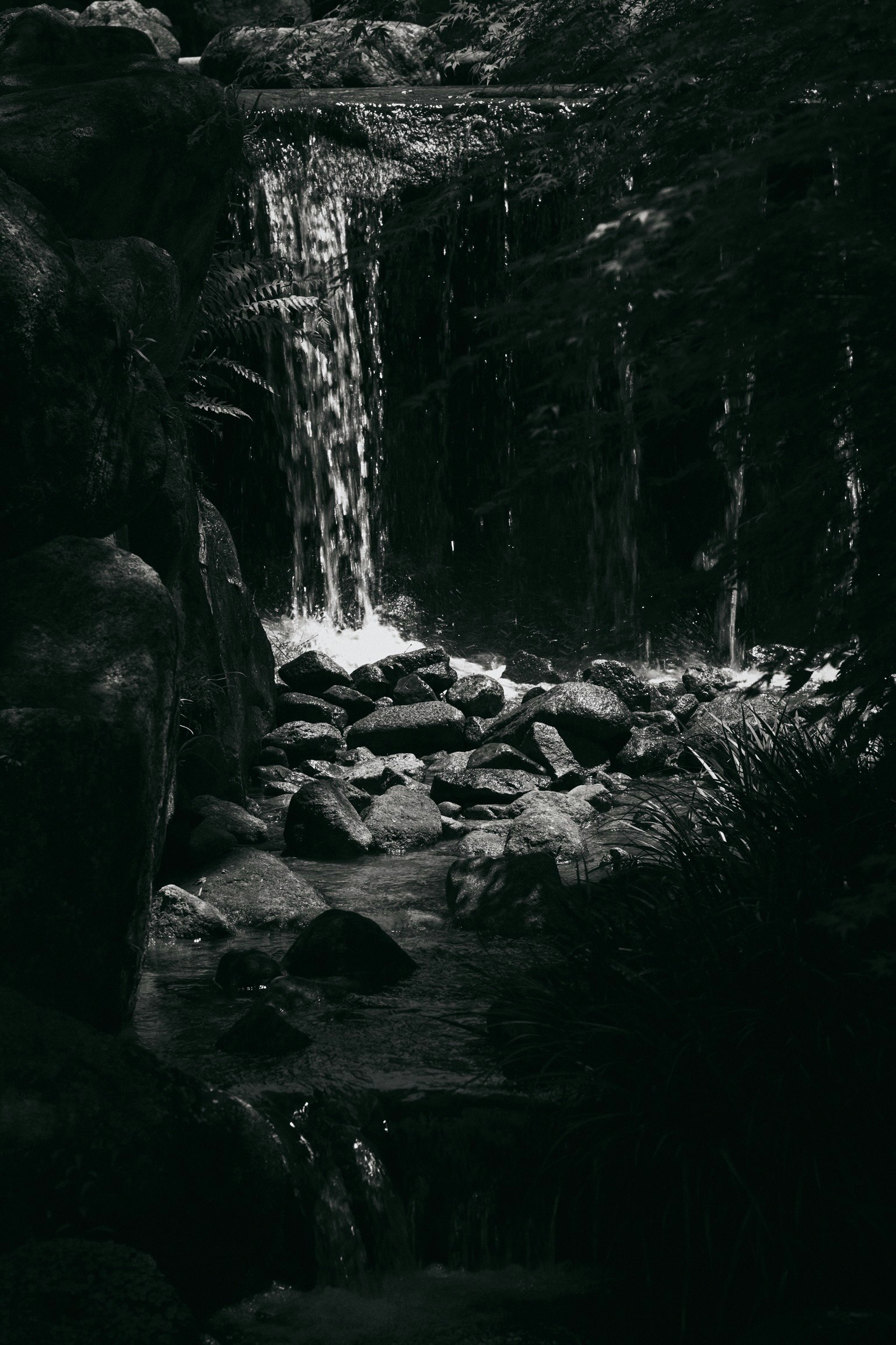Black and white photo of a waterfall with visible rocks and flowing water
