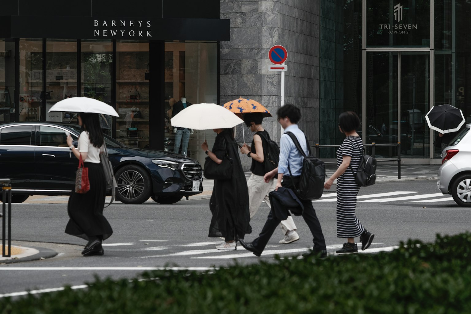 Persone che attraversano la strada con ombrelli in un ambiente urbano