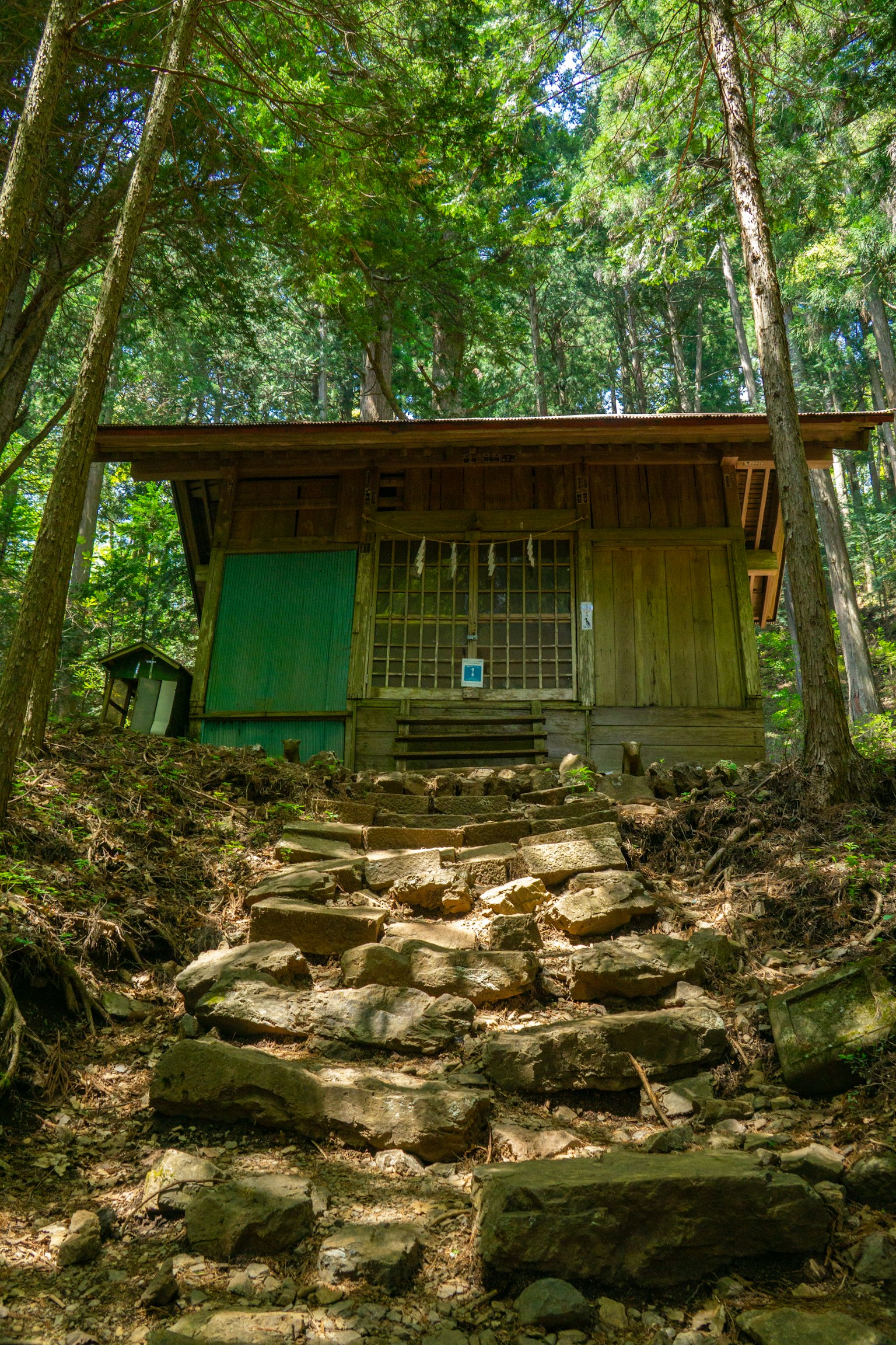 Petit bâtiment en bois dans la forêt avec des escaliers en pierre