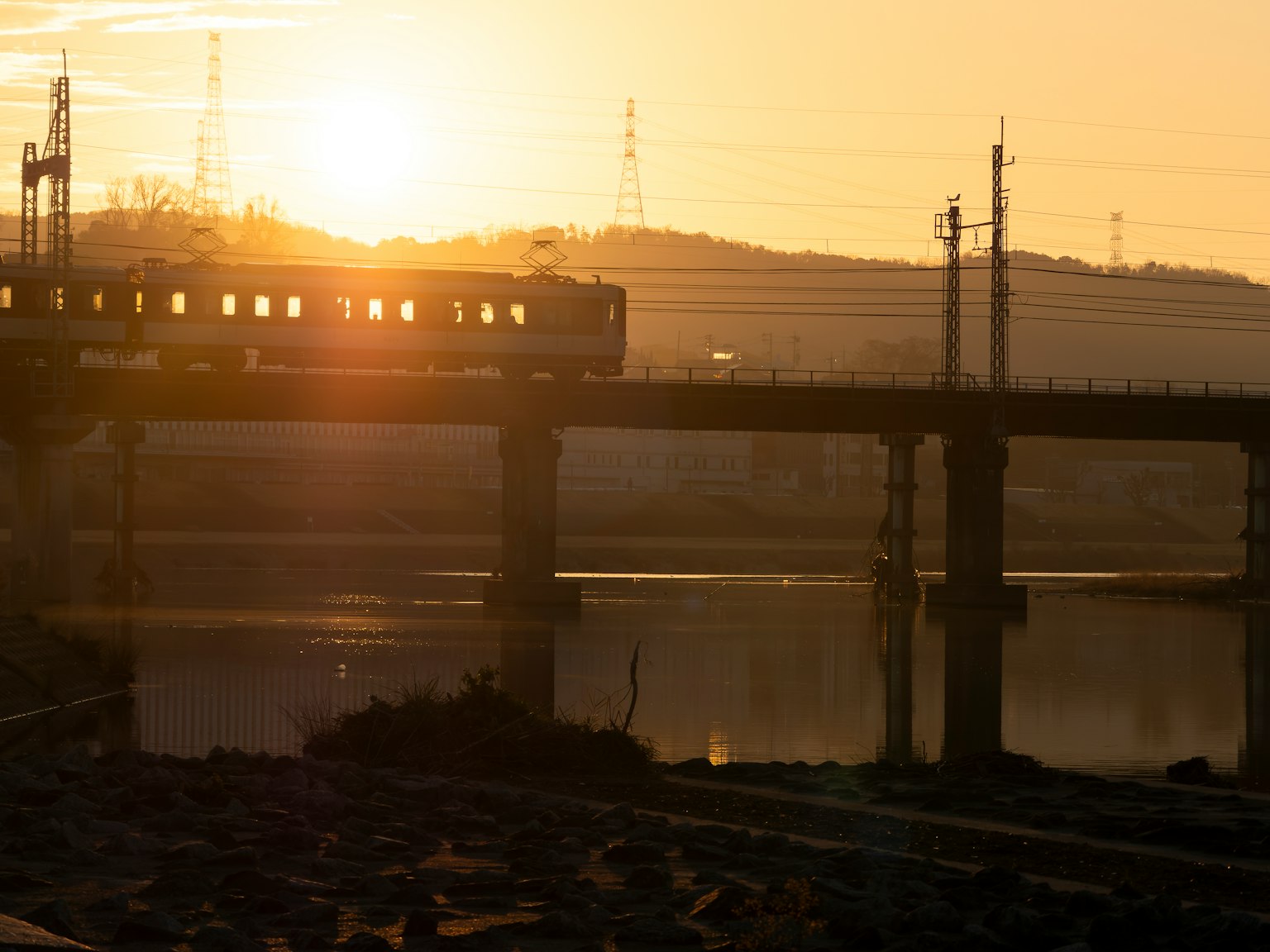夕陽下的火車穿越橋樑，水面上有倒影