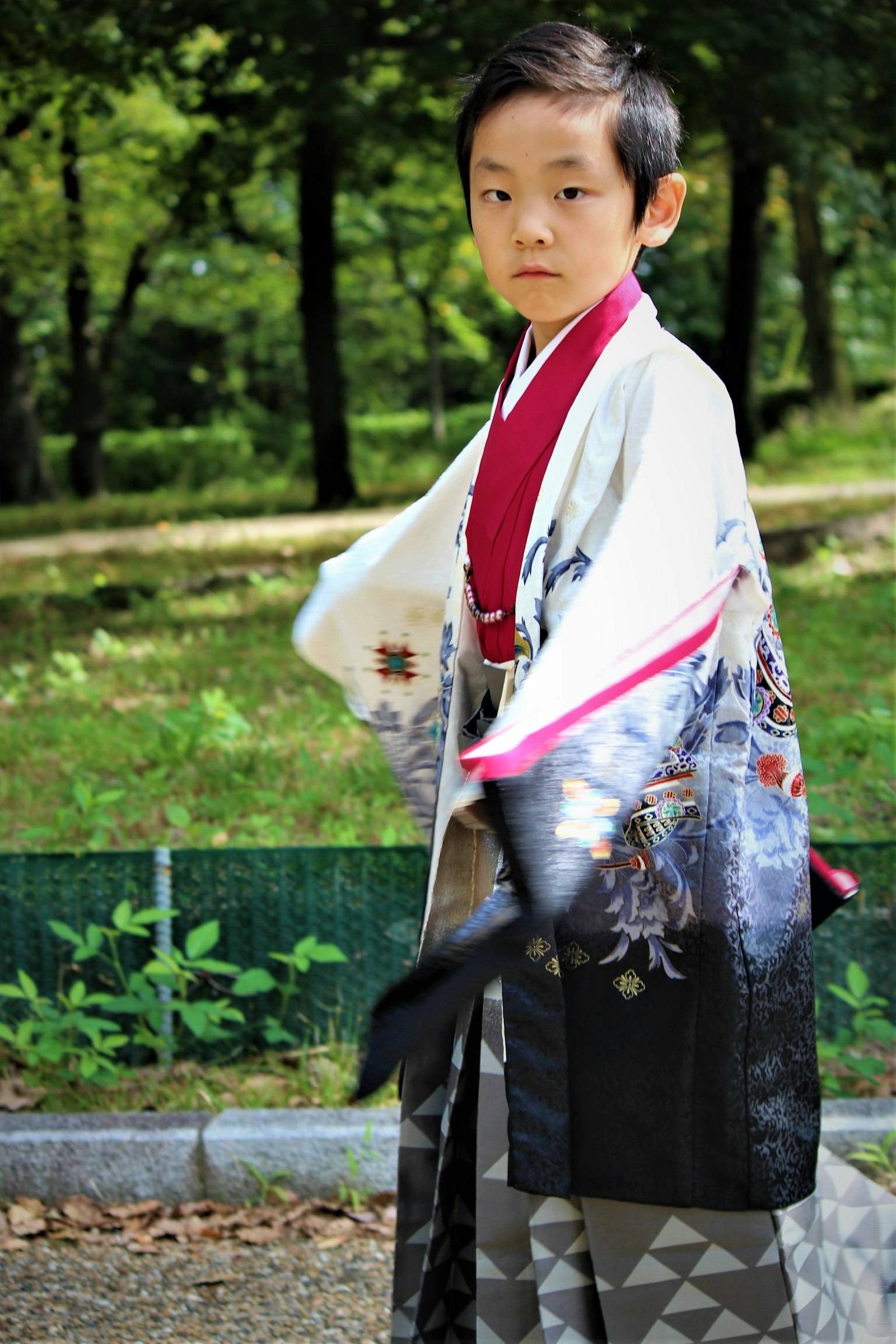 Un garçon portant un kimono traditionnel debout dans un parc