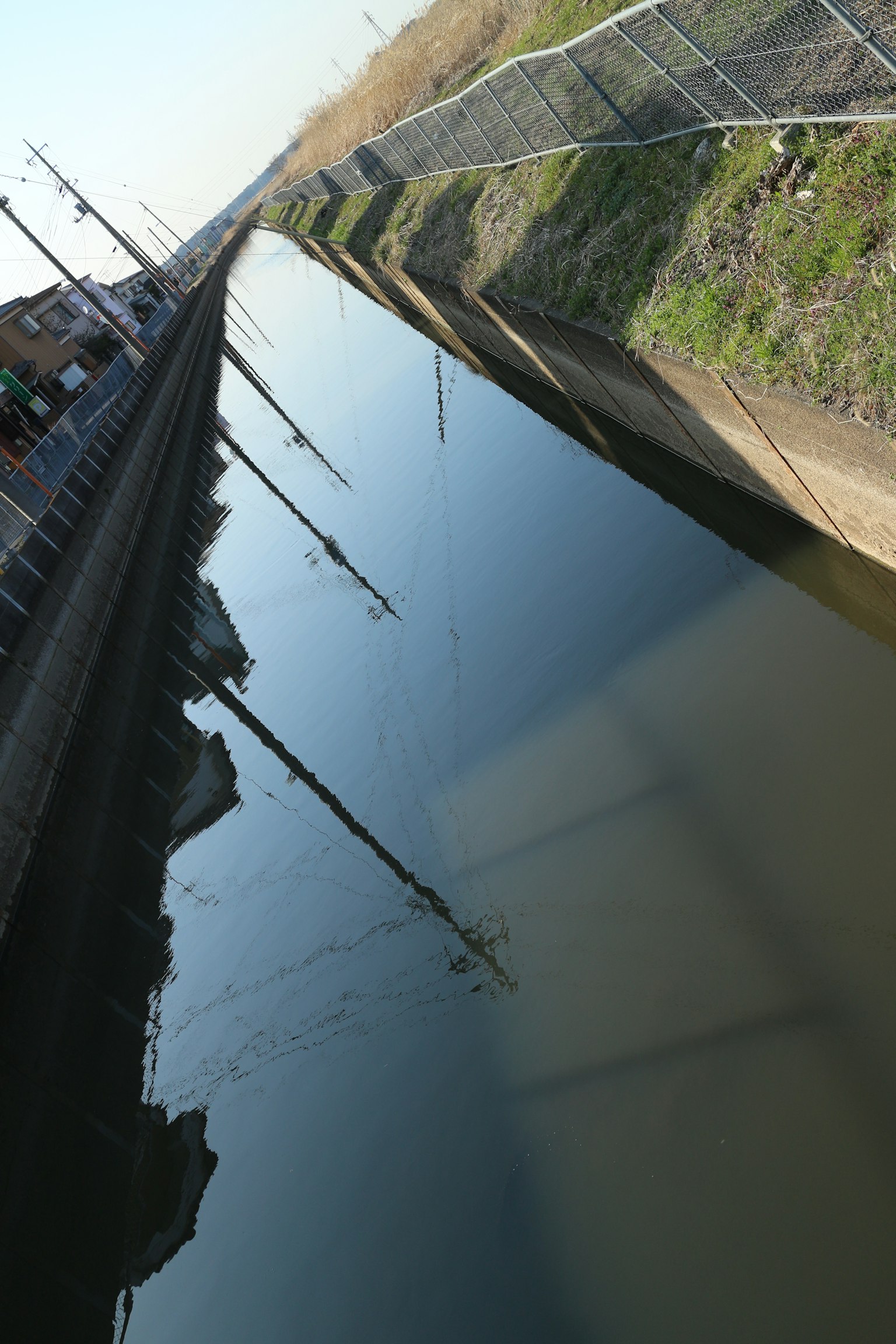 Canal tranquilo que refleja postes de servicios públicos y paisaje circundante