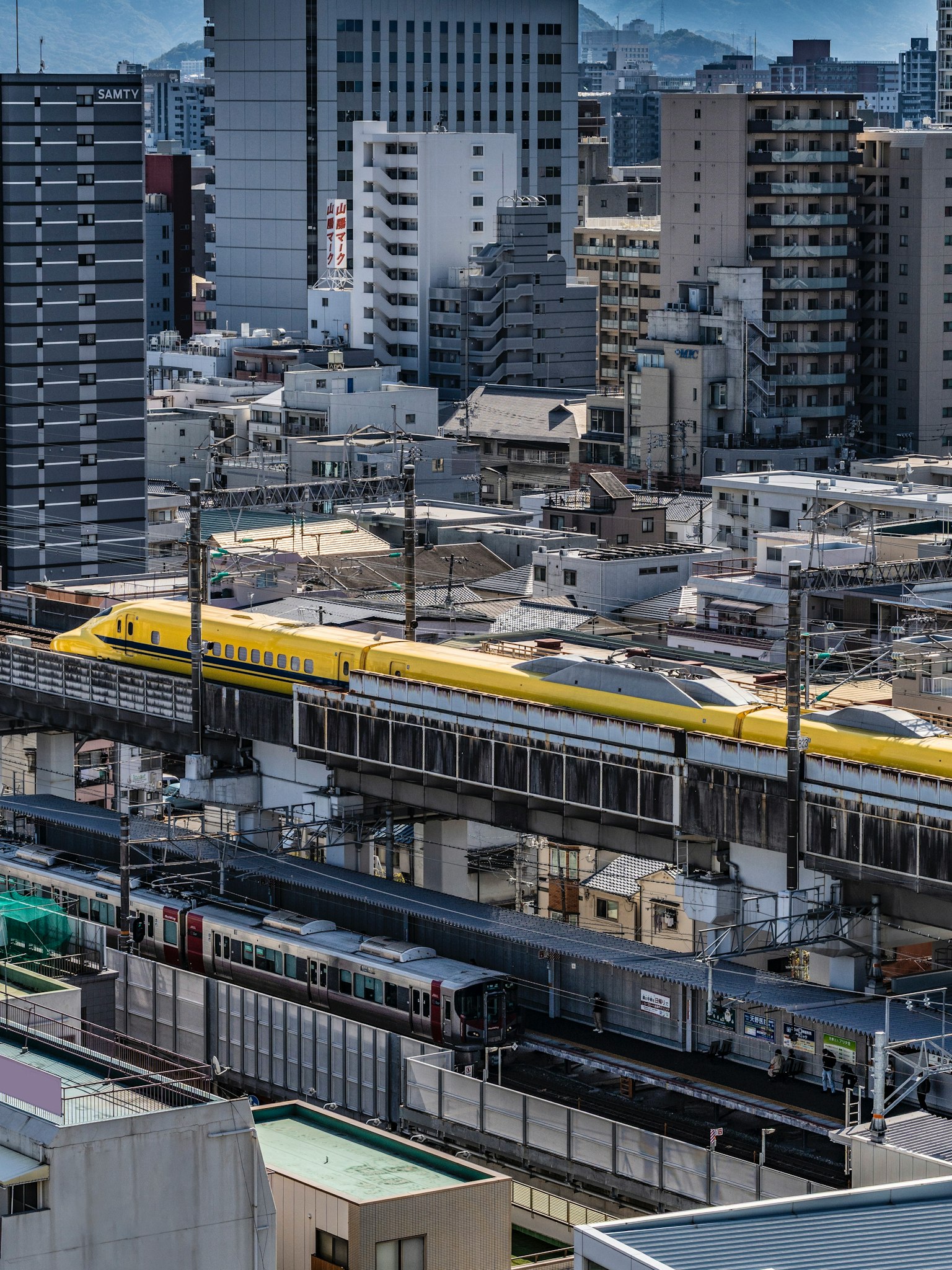 都市の高層ビルと鉄道の風景 黄色い電車が走る