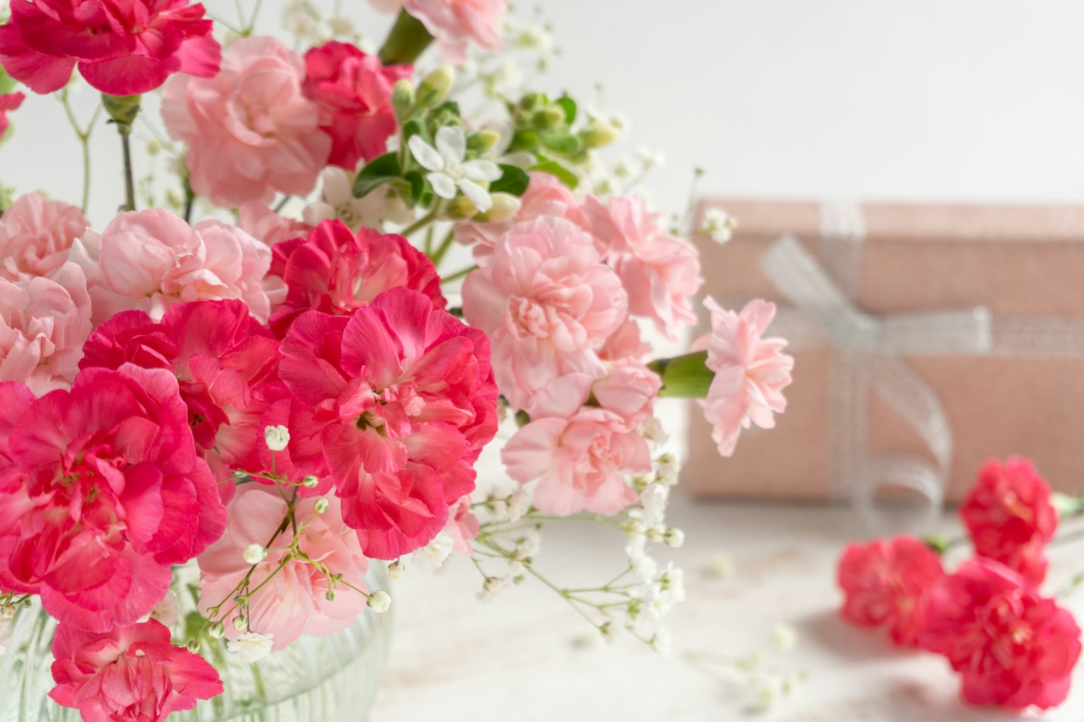 Un bouquet de fleurs roses et rouges dans un vase en verre avec des accents blancs délicats