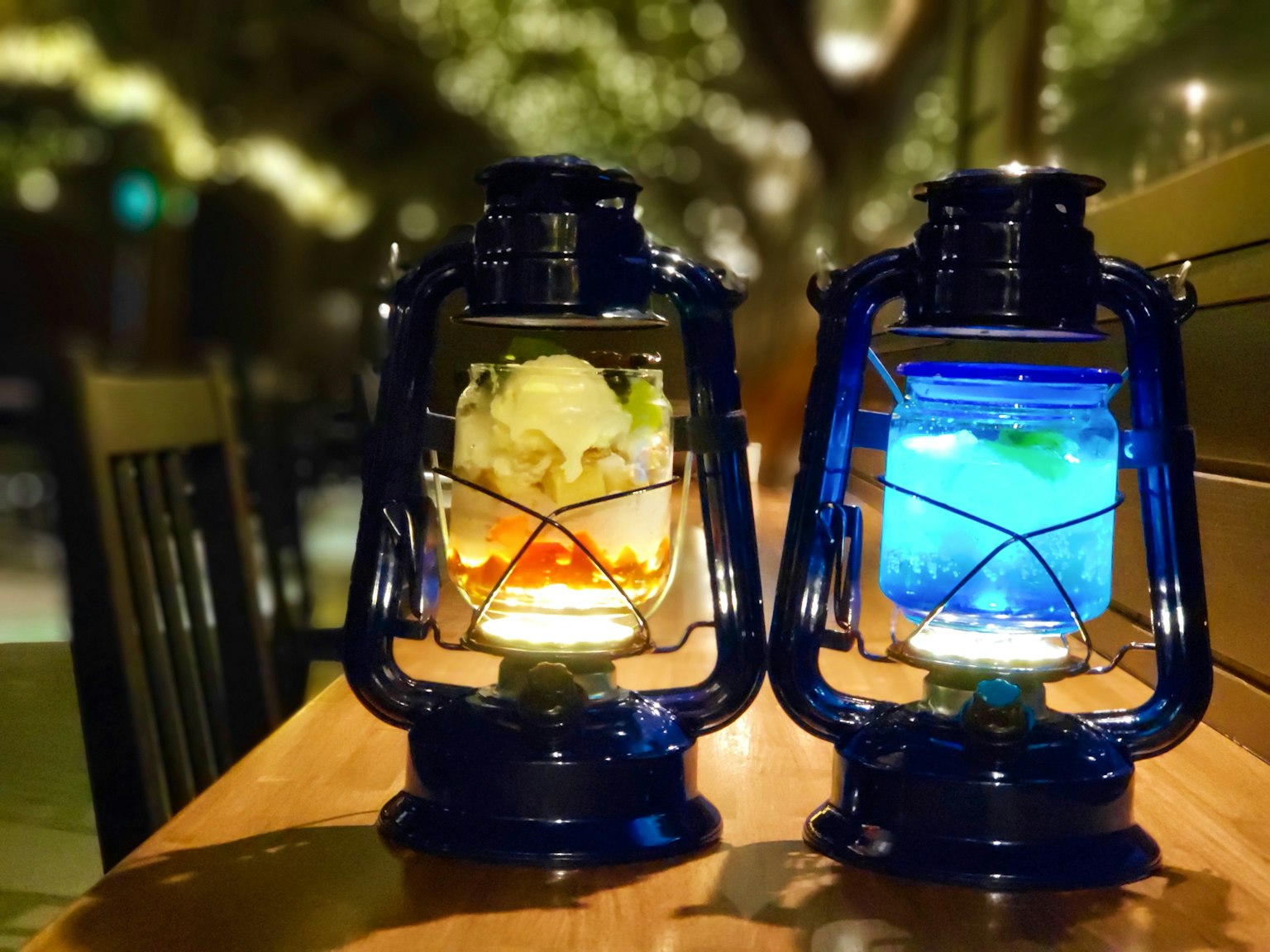 Dua lampu yang memancarkan cahaya biru dan oranye diletakkan di atas meja kayu
