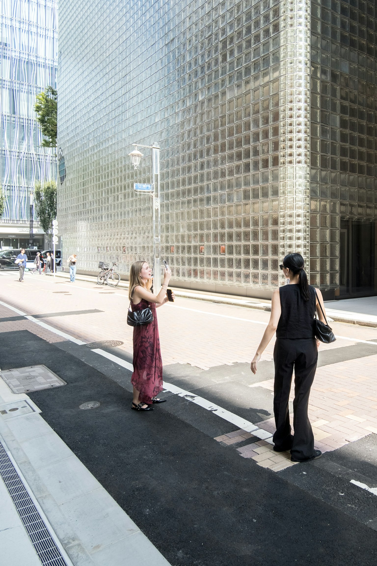 Dos mujeres caminando frente a un edificio moderno de vidrio