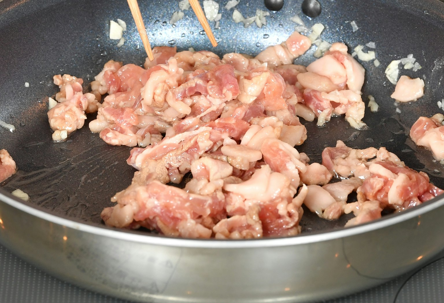 In einer Pfanne brät geschnittenes Schweinefleisch mit Essstäbchen