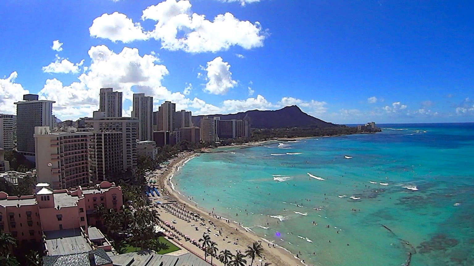 Una vista panorámica de la playa de Waikiki con aguas turquesas y edificios altos