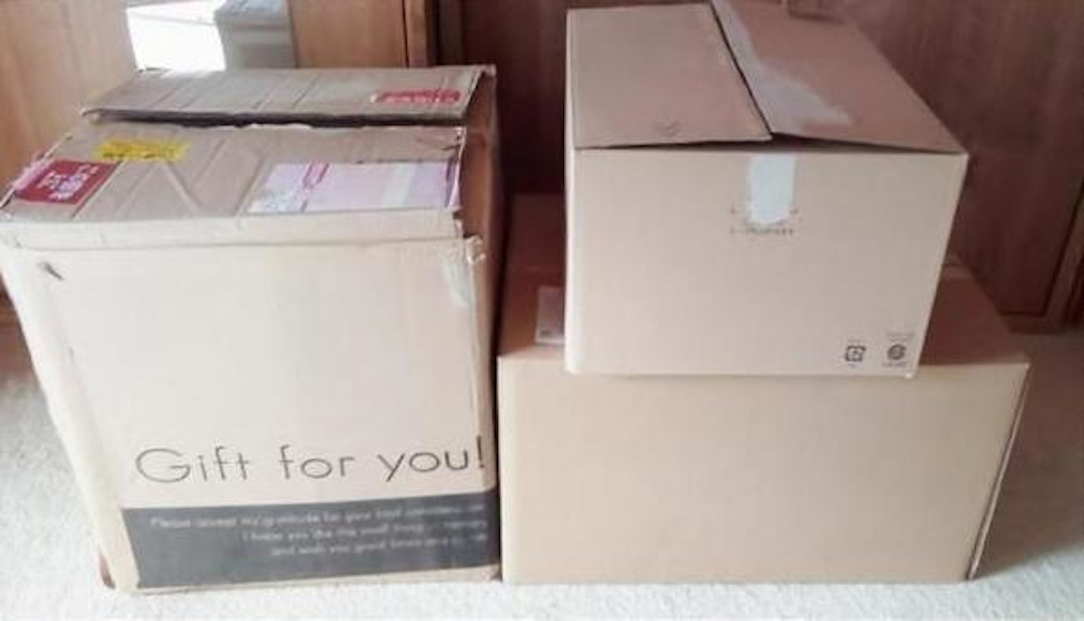 いくつかの段ボール箱が積み重ねられていて、特に「Gift for you」というメッセージが見える箱がある