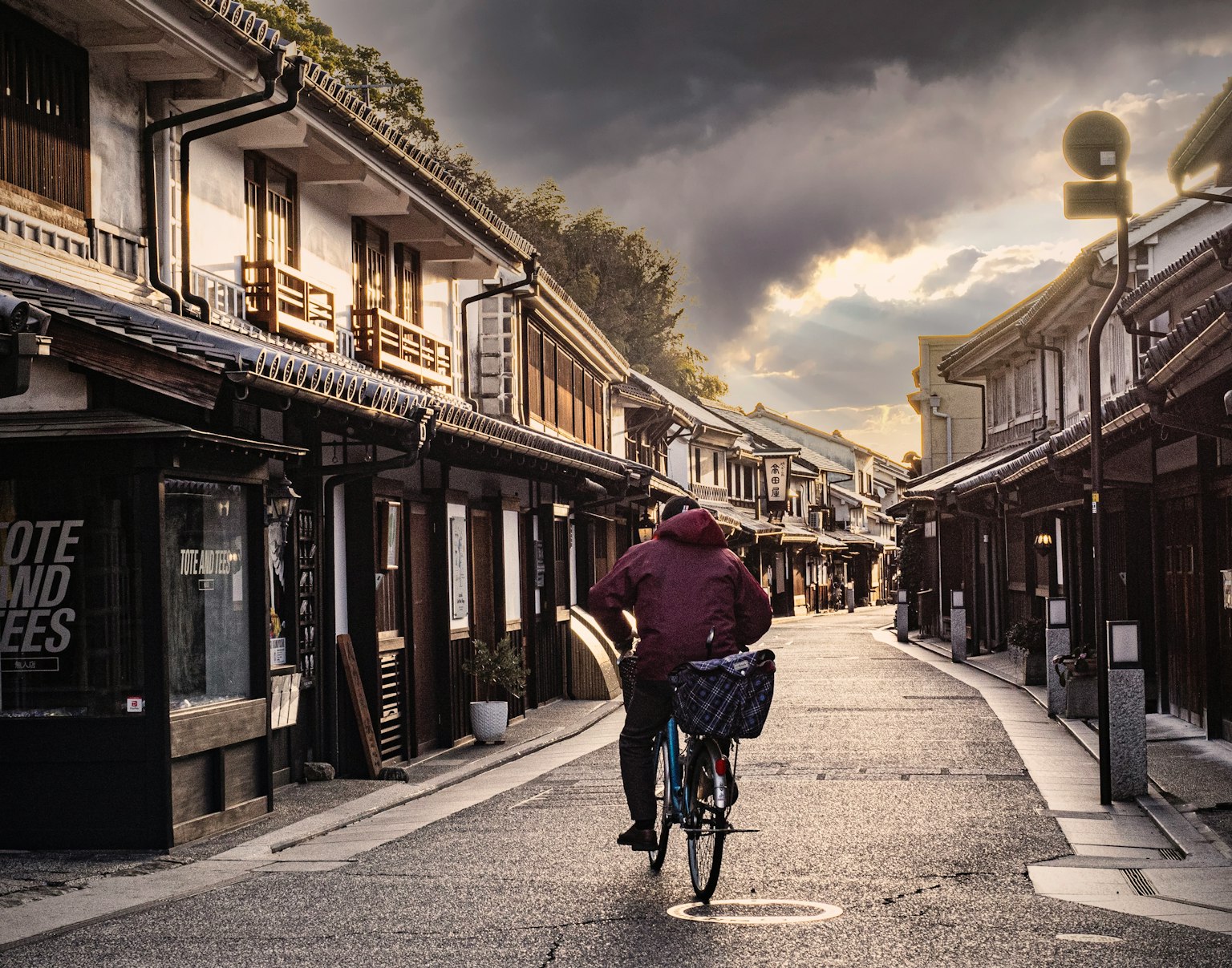 Person riding a bicycle in a traditional street with cloudy sky