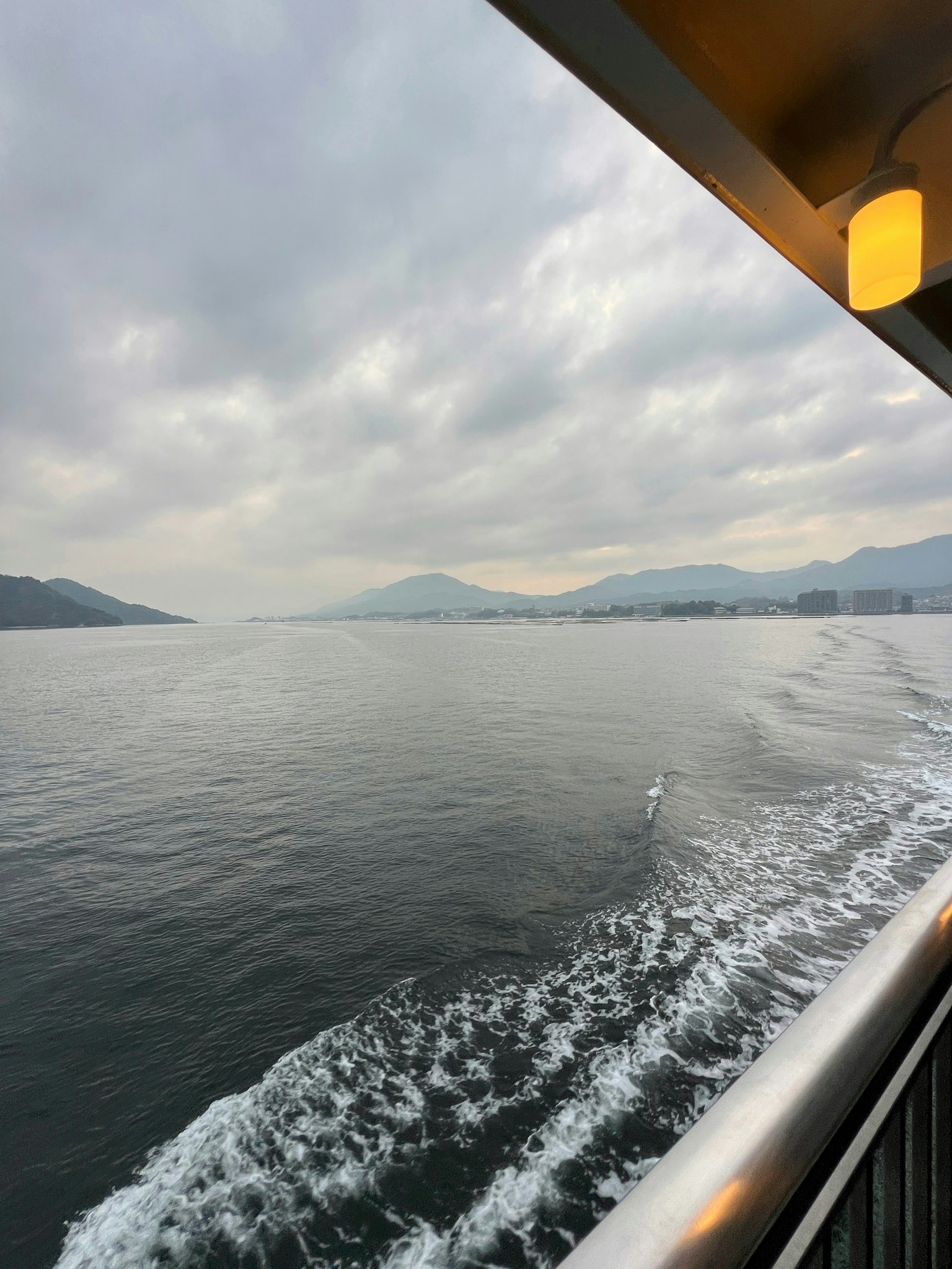 Paisaje marino sereno con cielo nublado y barandilla de barco en vista
