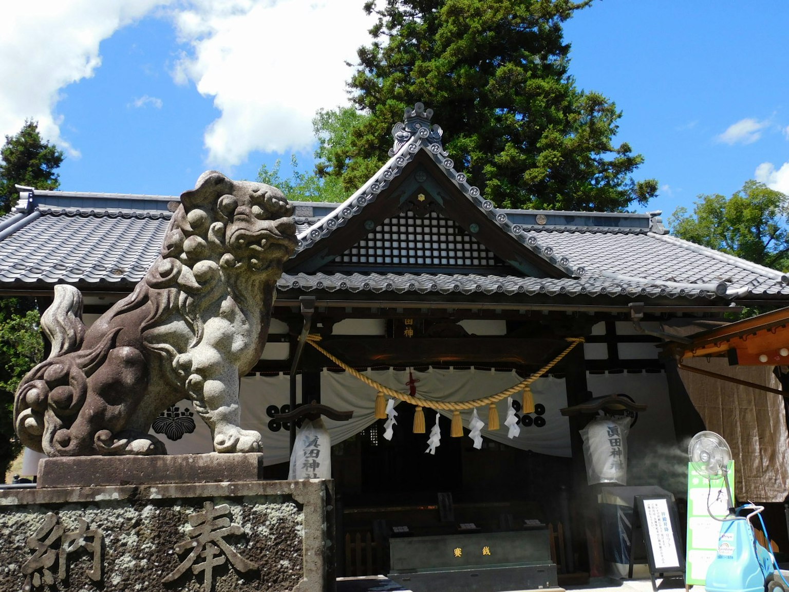 寺庙入口有守护狮子雕像和传统屋顶在蓝天之下