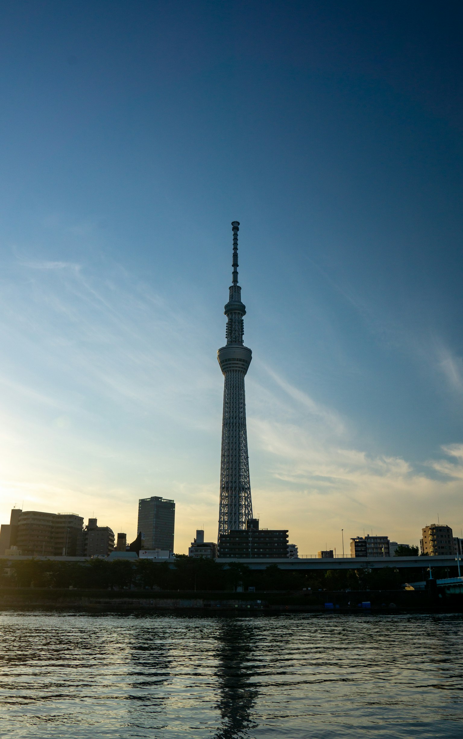 Silhouette des Tokyo Skytree, die sich bei Sonnenuntergang im Wasser spiegelt
