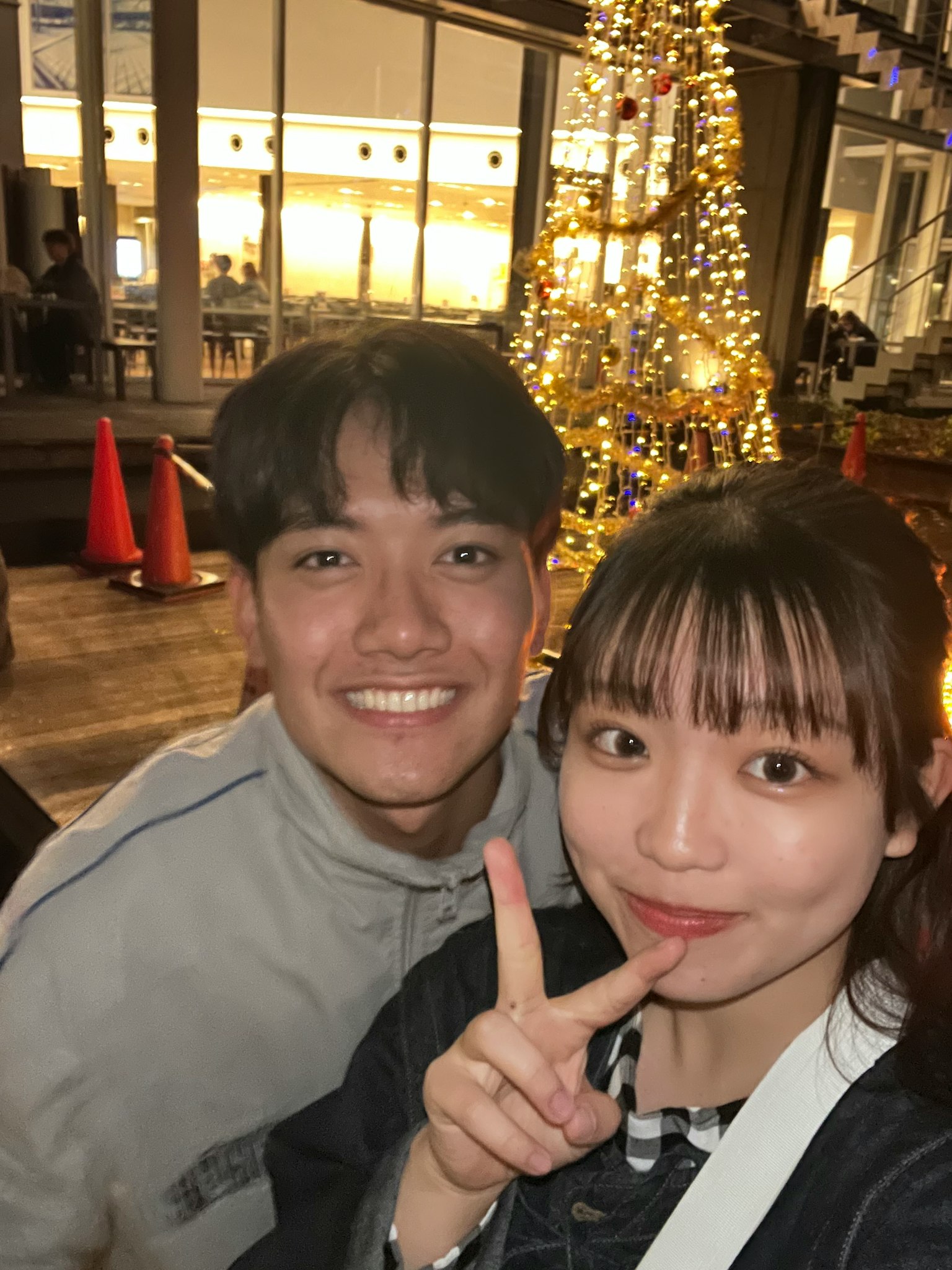 คู่หนุ่มสาวยิ้มอยู่หน้าต้นคริสต์มาส