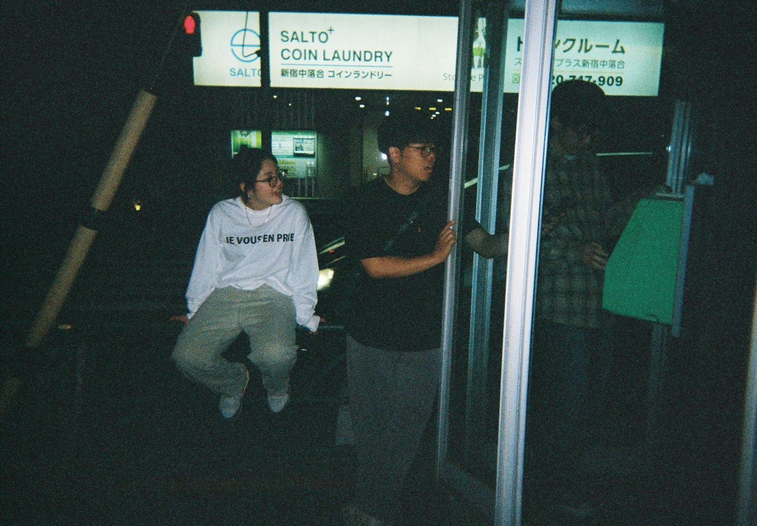 夜のコインランドリー前で立つ2人