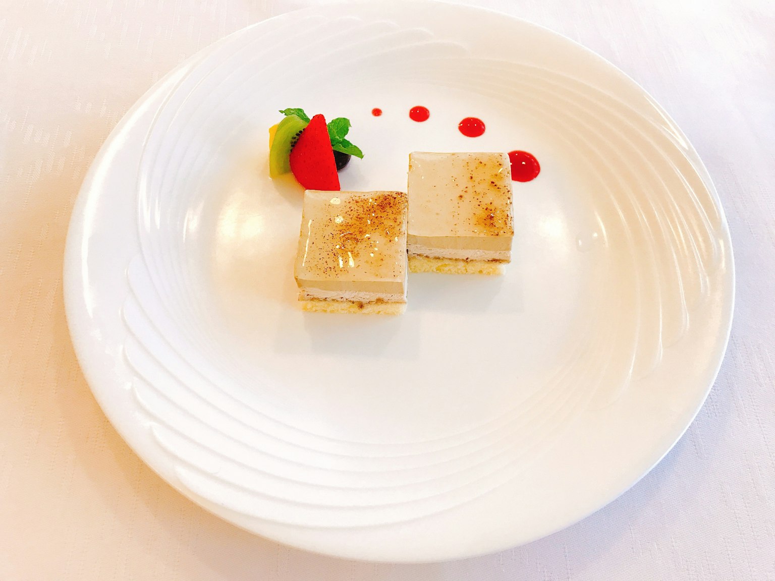 Due dolci disposti su un piatto bianco con decorazione di salsa rossa