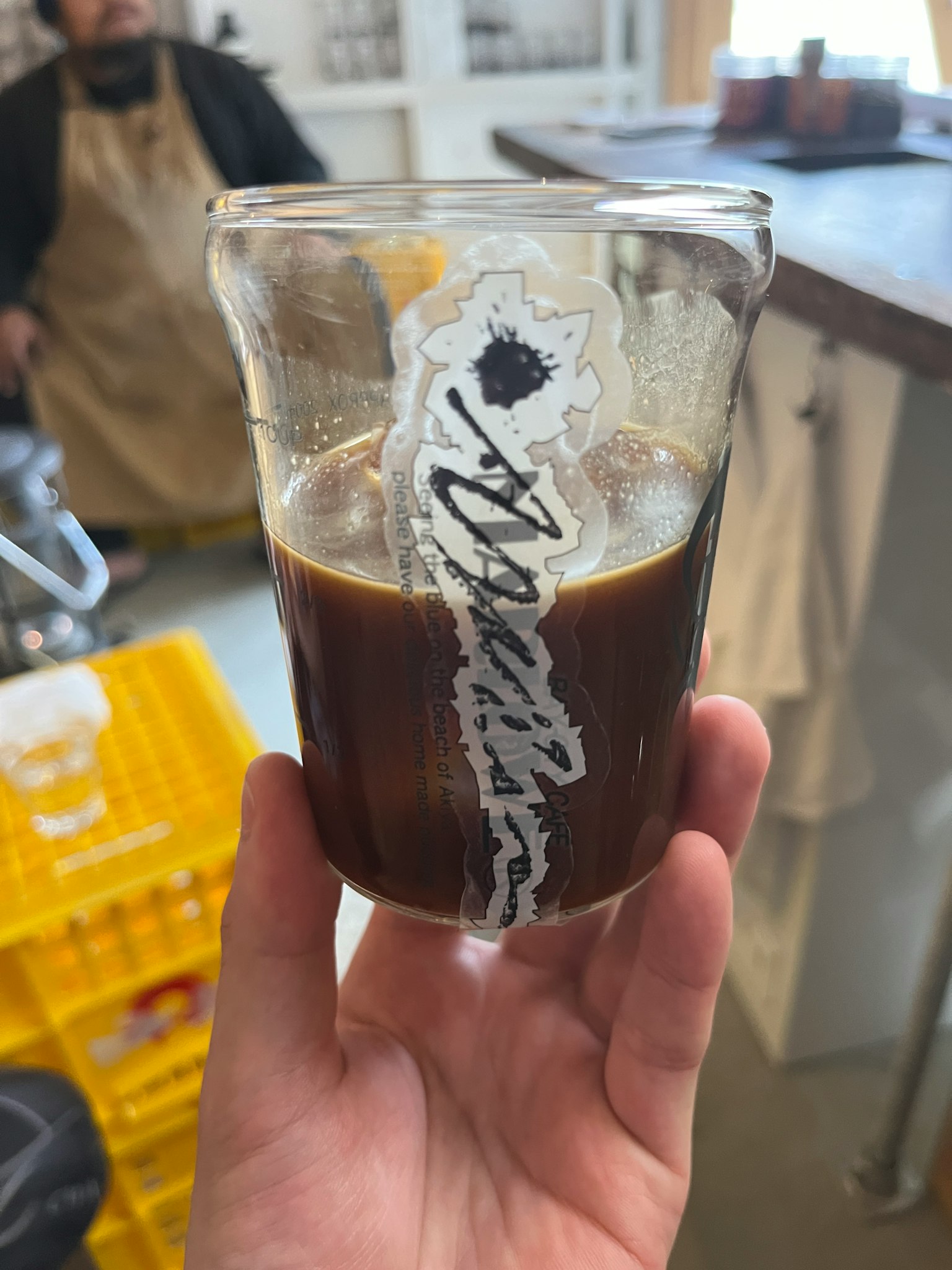 一隻手握著裝滿深色咖啡的玻璃杯