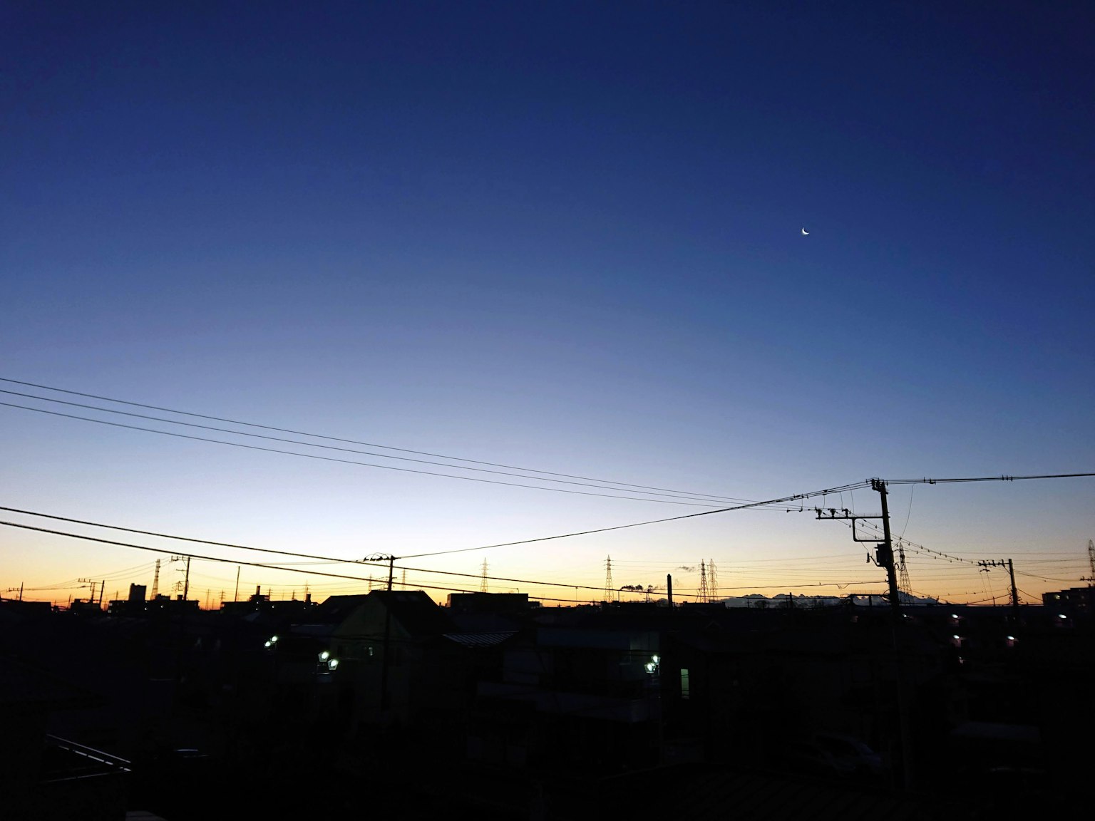 Cielo al crepuscolo con silhouette di edifici e linee elettriche