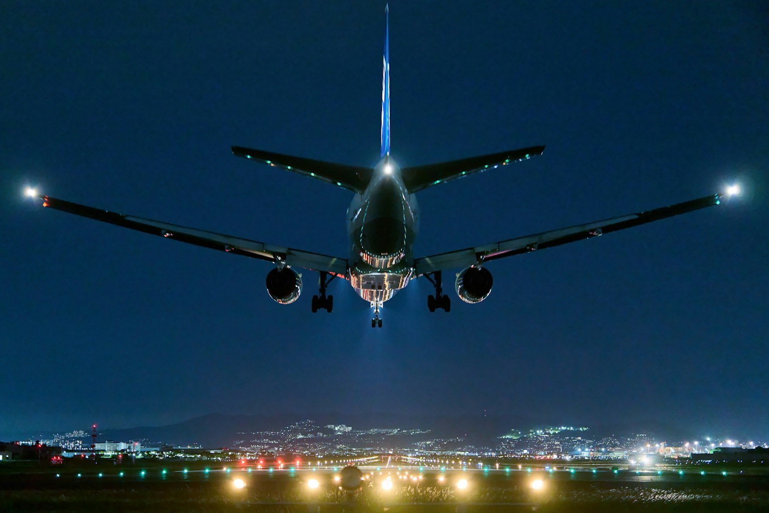 Avion en approche d'atterrissage de nuit éclairé par les lumières de la piste et les lumières de la ville