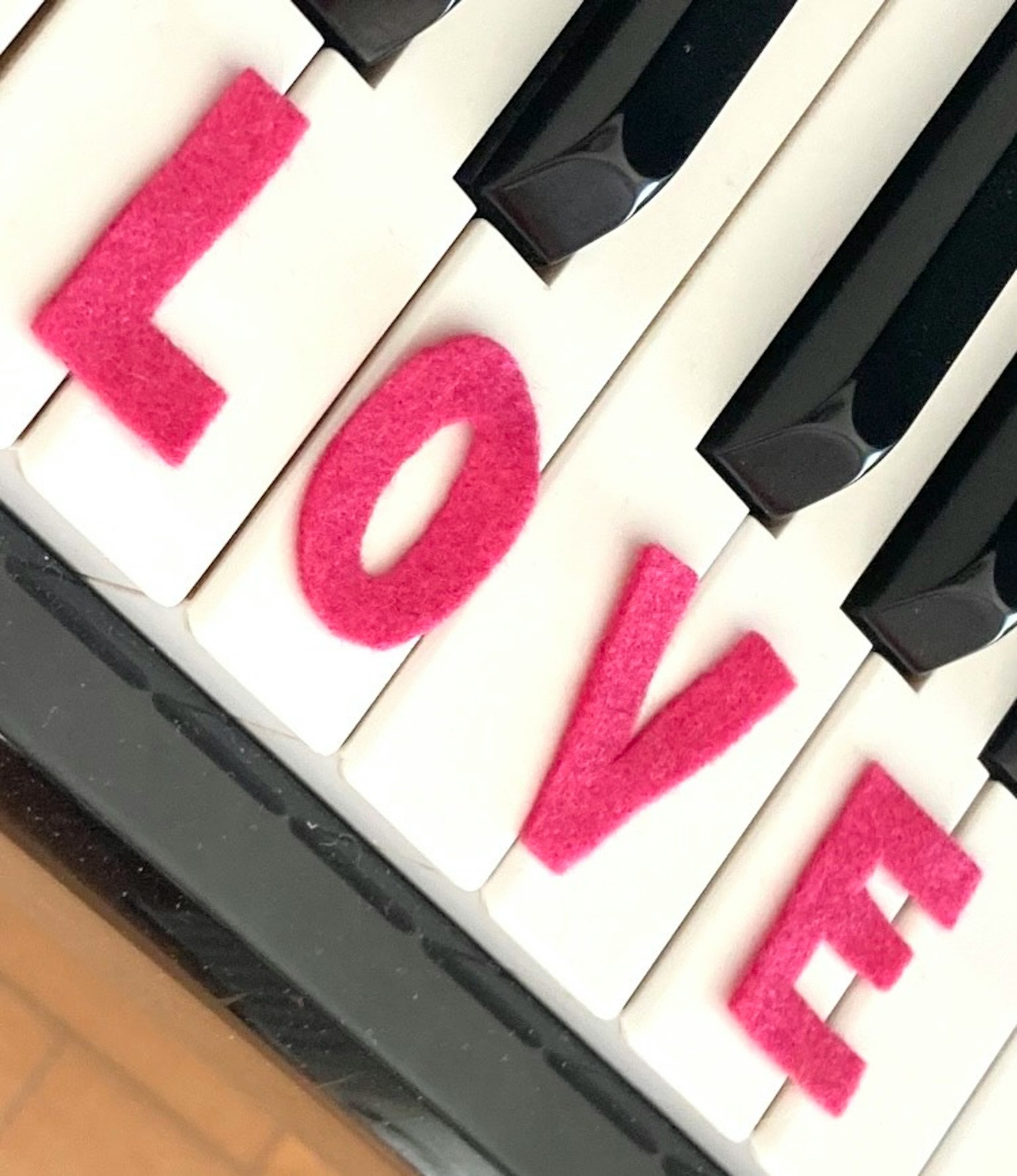 白色钢琴键上拼写“LOVE”的粉色字母