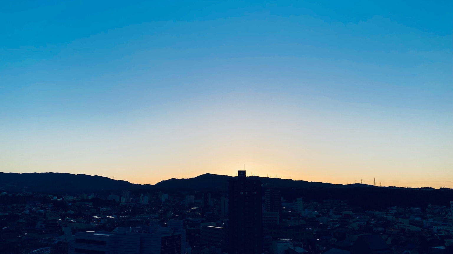 Silhouette de montañas con el horizonte de la ciudad al anochecer