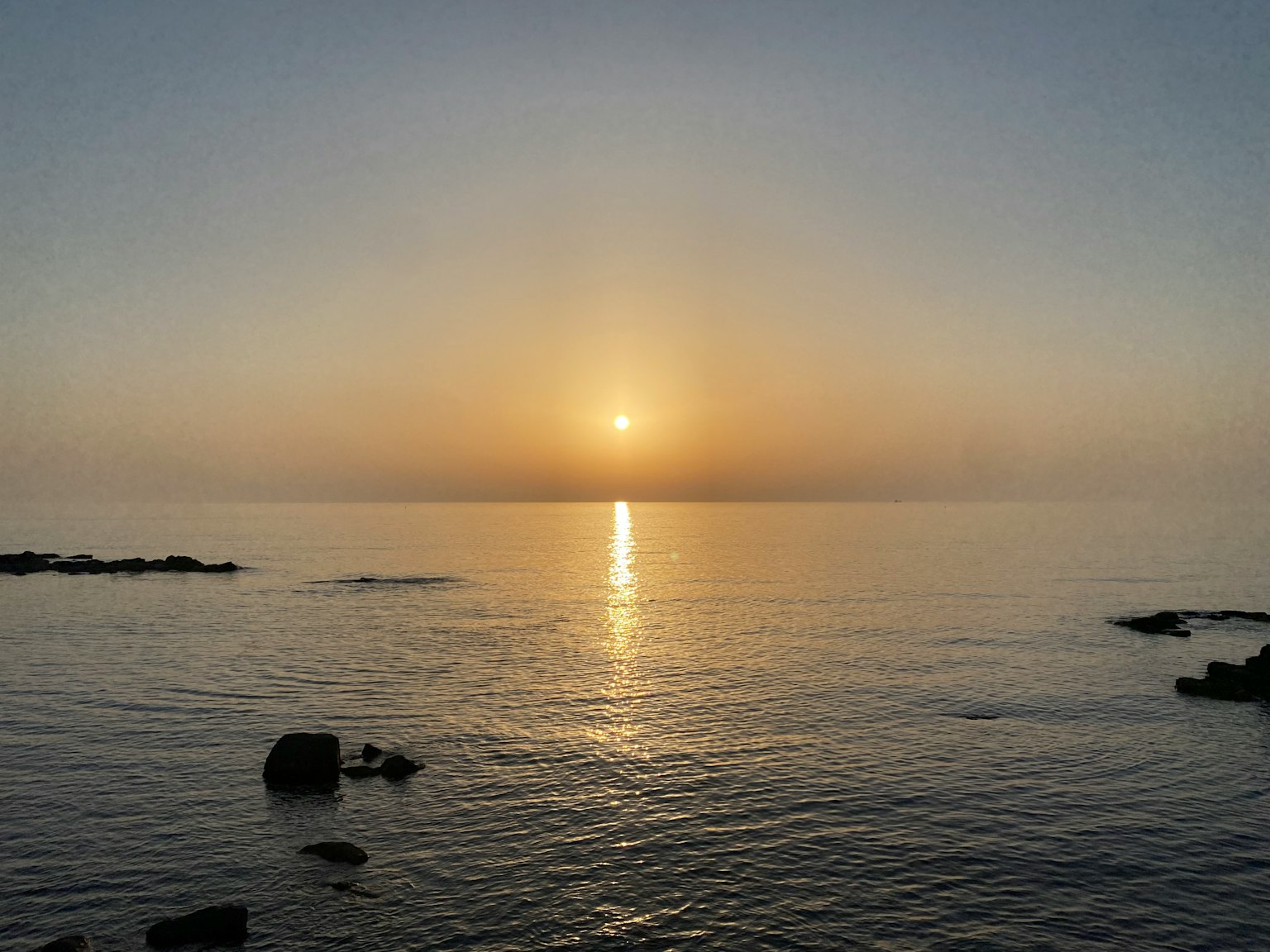 Mare calmo con un'alba Sole che sorge e riflessione sull'acqua