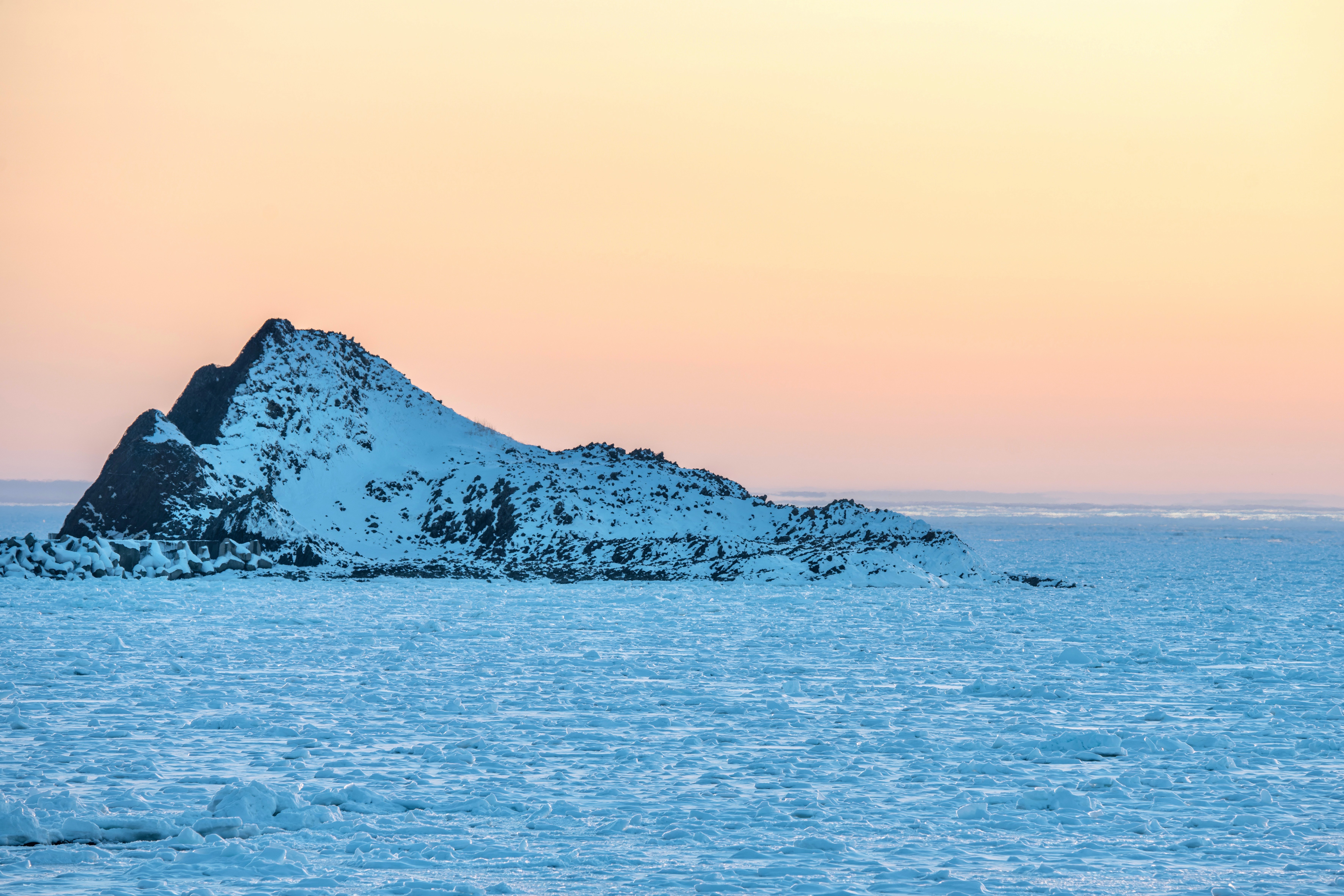 Isla cubierta de nieve flotando en un mar tranquilo durante un hermoso atardecer
