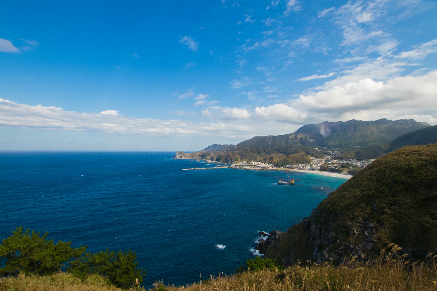 Pemandangan pantai yang indah dengan laut biru dan langit serta gunung di latar belakang