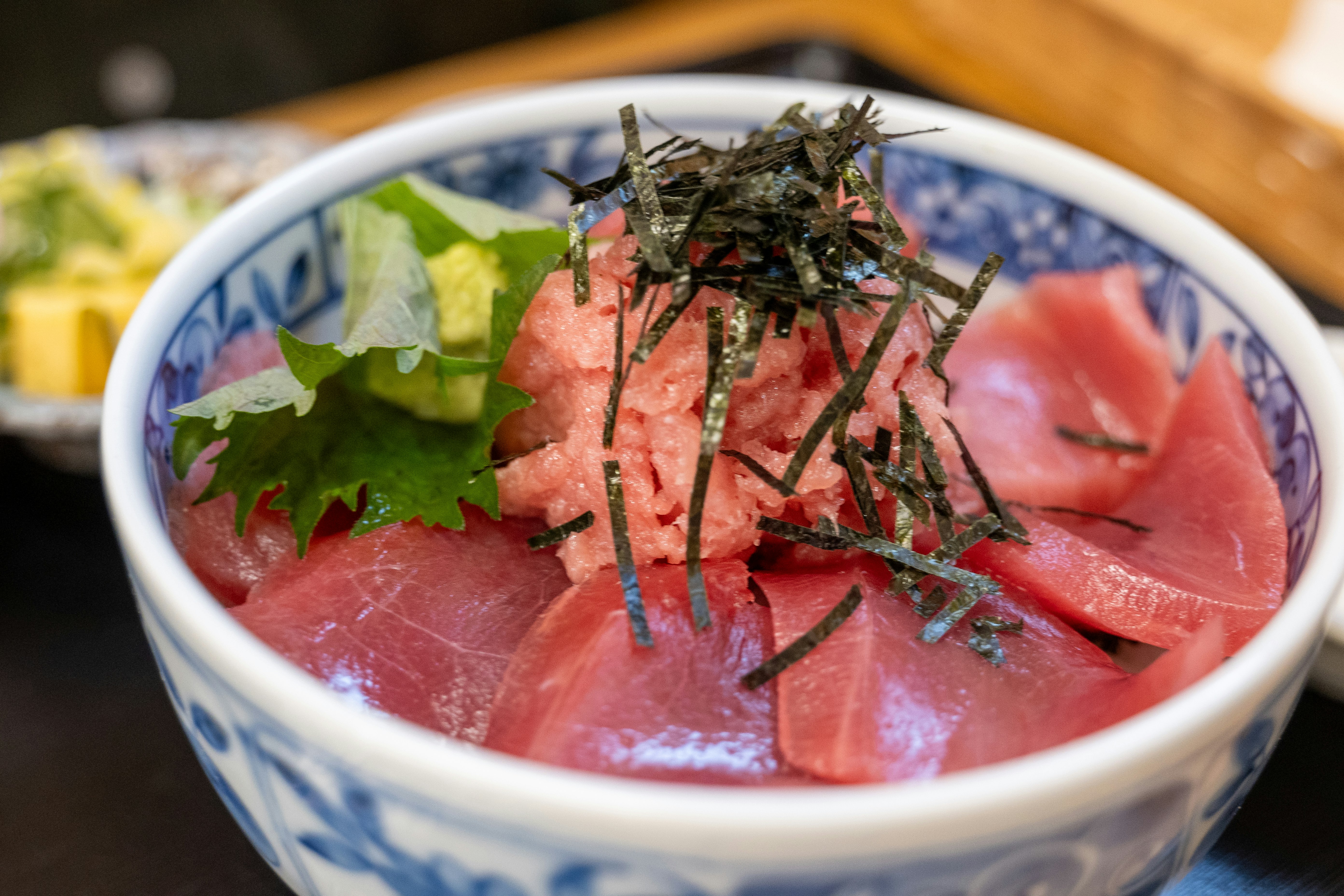 鮮やかなマグロの刺身が盛られた丼 その上にはわさびと海苔がトッピングされている