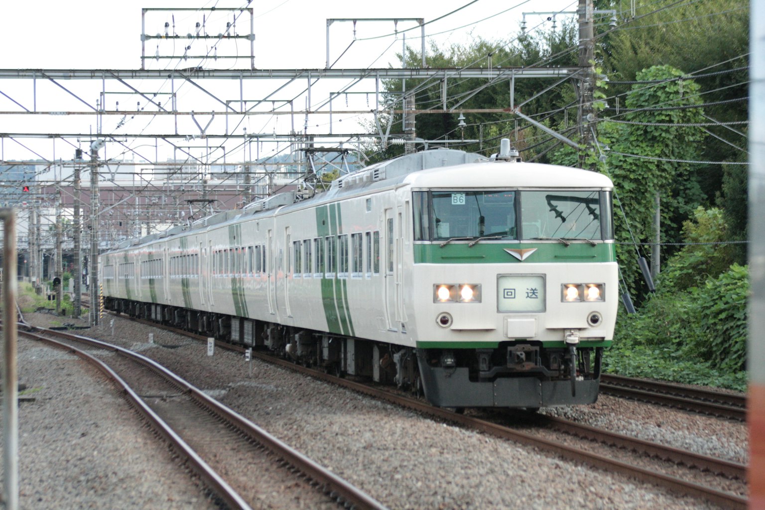 Sebuah kereta Jepang dengan garis hijau melaju di rel melengkung