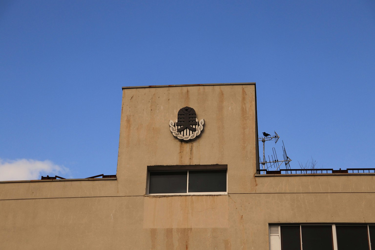 Emblema simbólico en la parte superior de un edificio con cielo azul claro