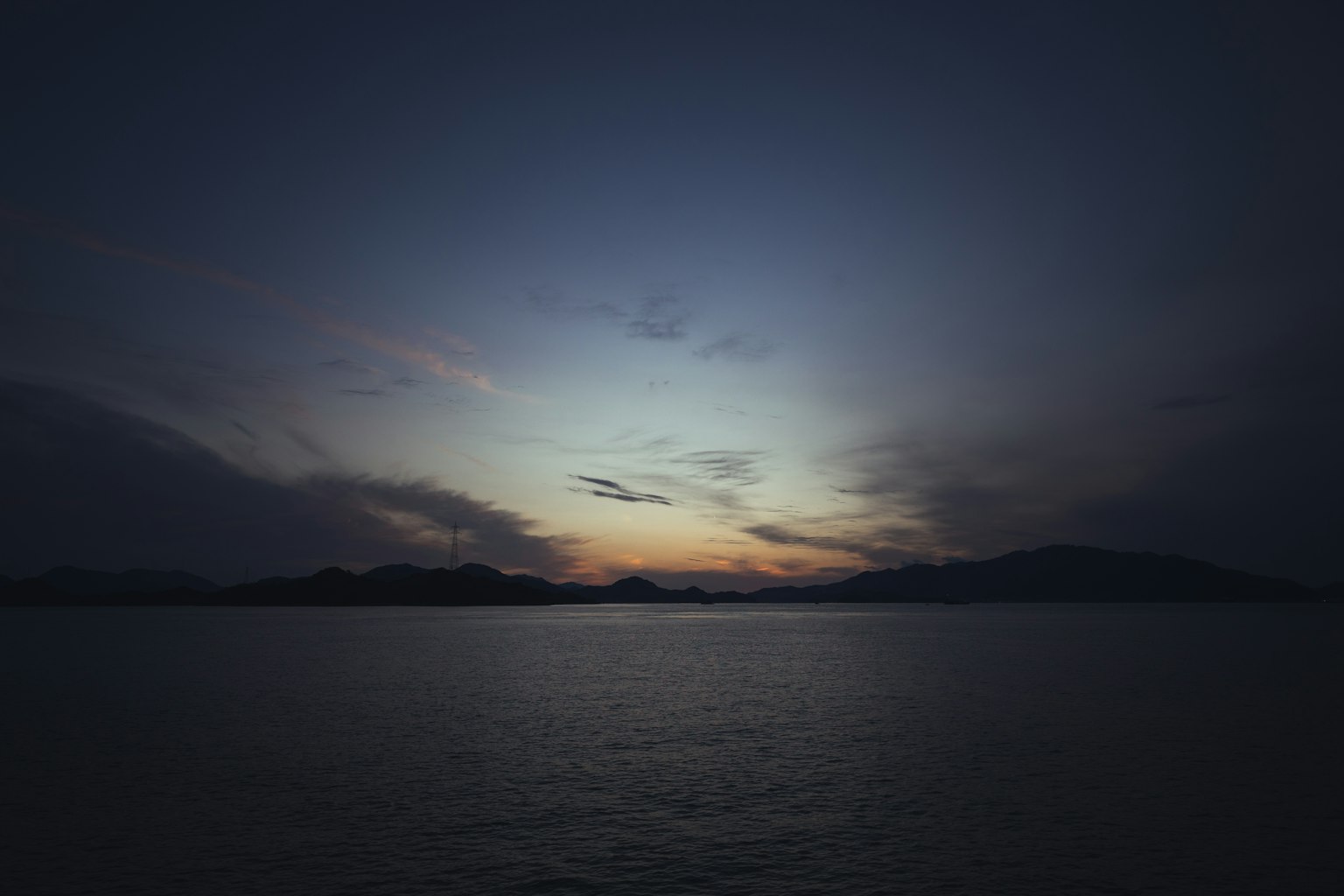 Danau tenang yang memantulkan langit senja dan siluet pegunungan