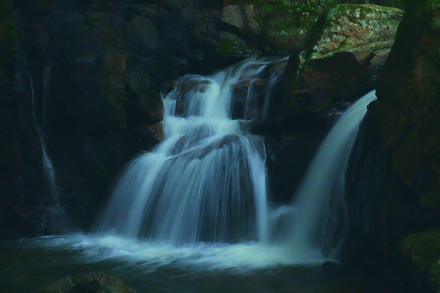 Schöner Wasserfall, der zwischen dunklen Felsen fließt