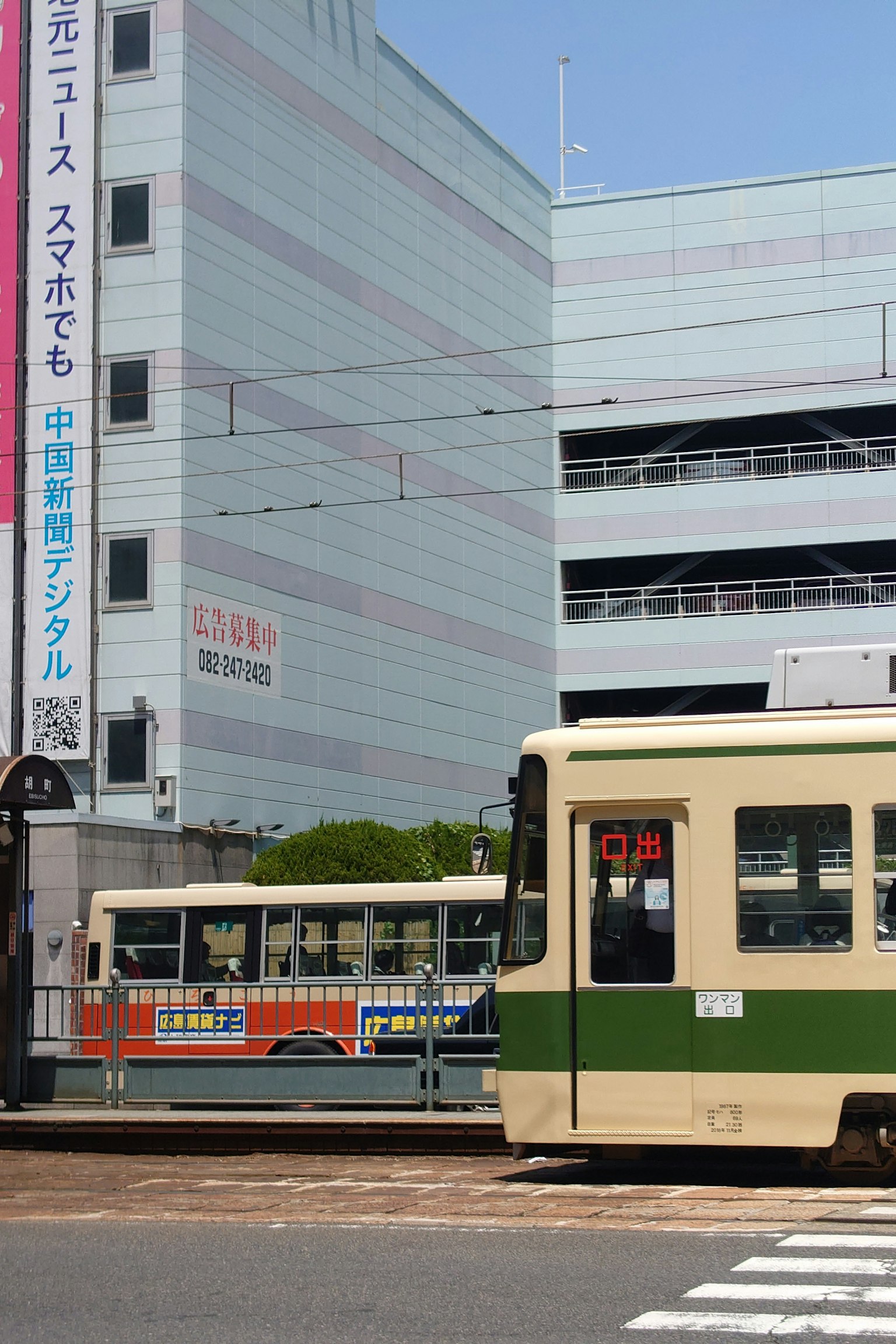 綠色和白色的電車停在交叉路口附近還有另一輛電車和商業大樓