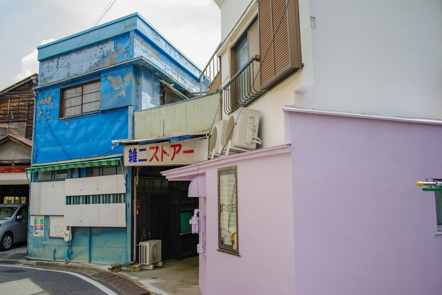 Vue de rue avec un bâtiment bleu et un magasin avec un mur violet