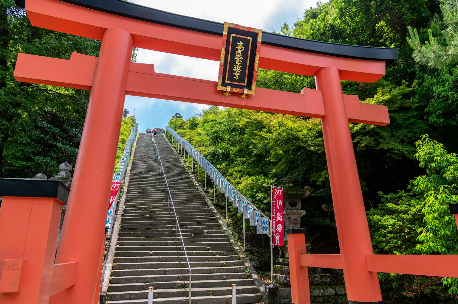 Portale torii rosso che conduce a scale di pietra circondate da vegetazione lussureggiante