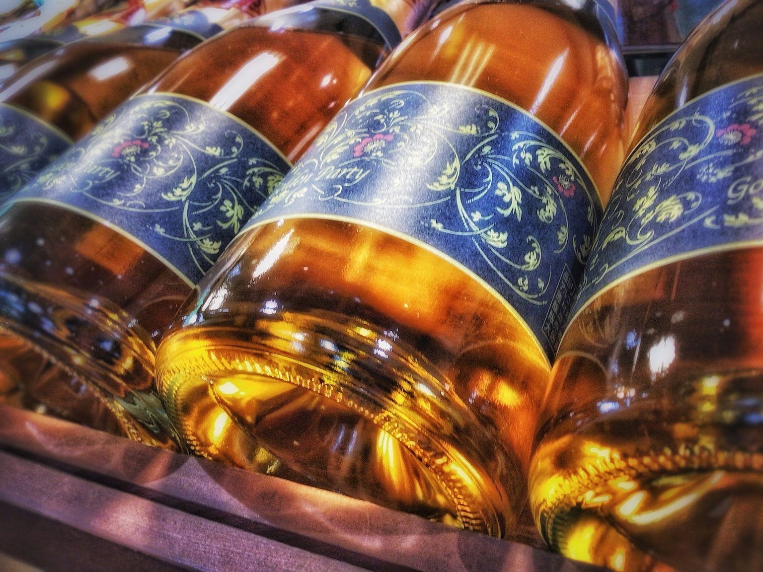Baris botol berisi cairan emas dengan label biru yang dekoratif