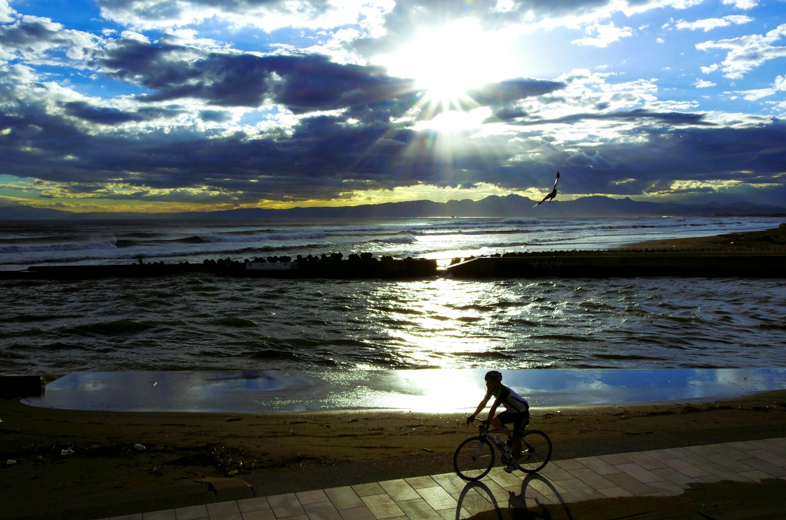 Người đi xe đạp dọc bờ biển với hoàng hôn tuyệt đẹp