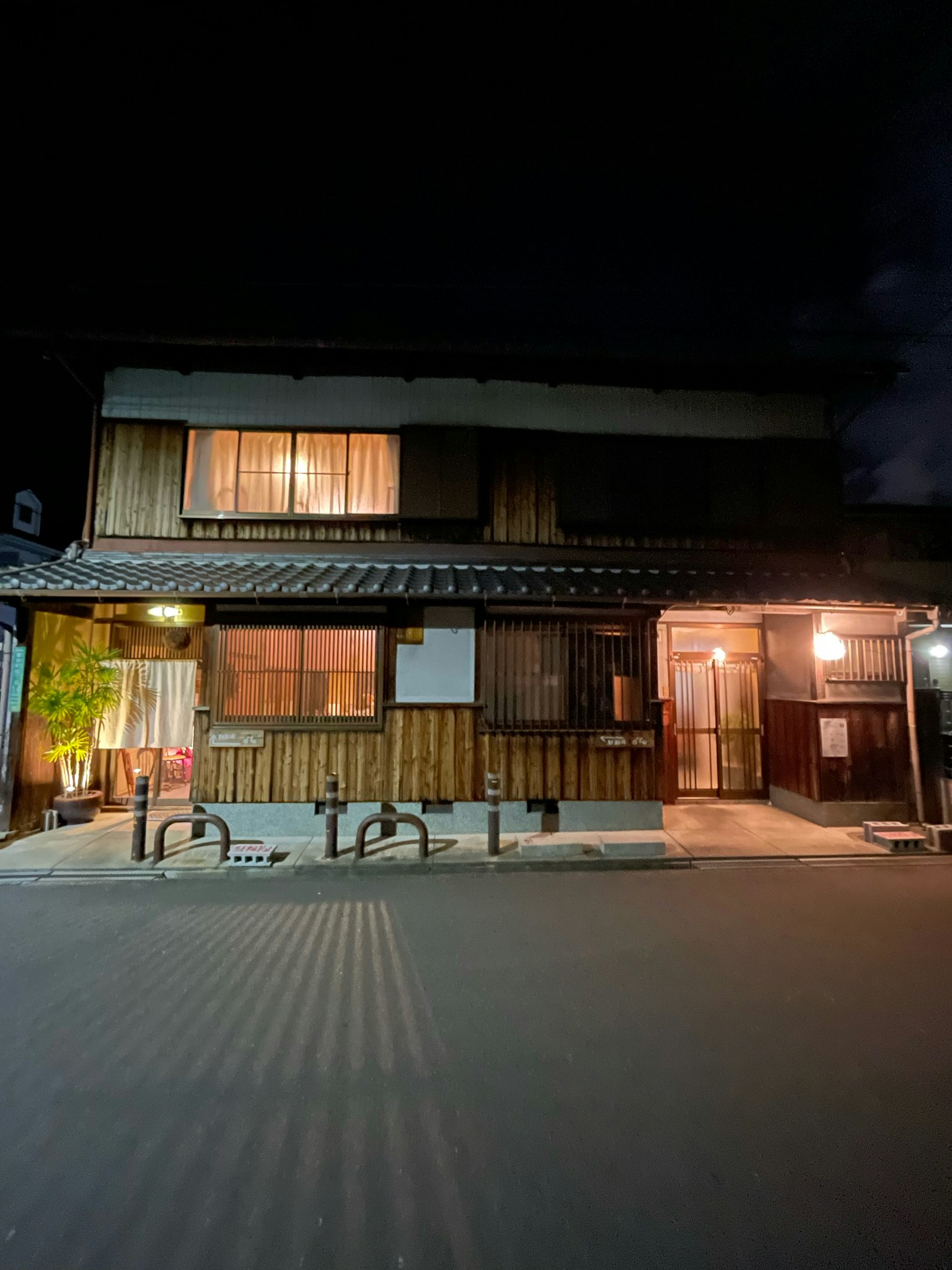 Exterior de una casa japonesa tradicional por la noche con paredes de madera y ventanas iluminadas