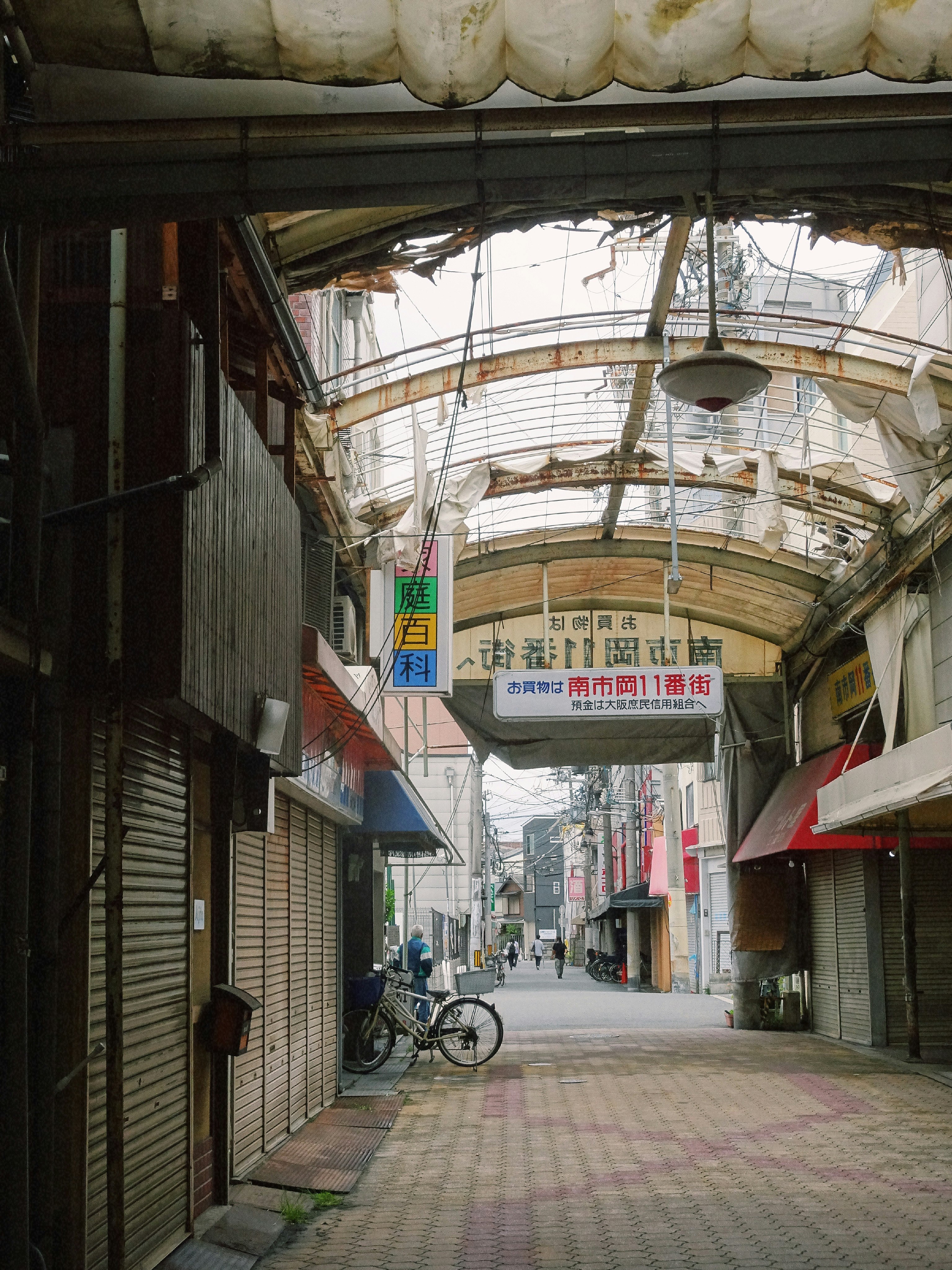 Bicycles along a narrow shopping alley under an arcade