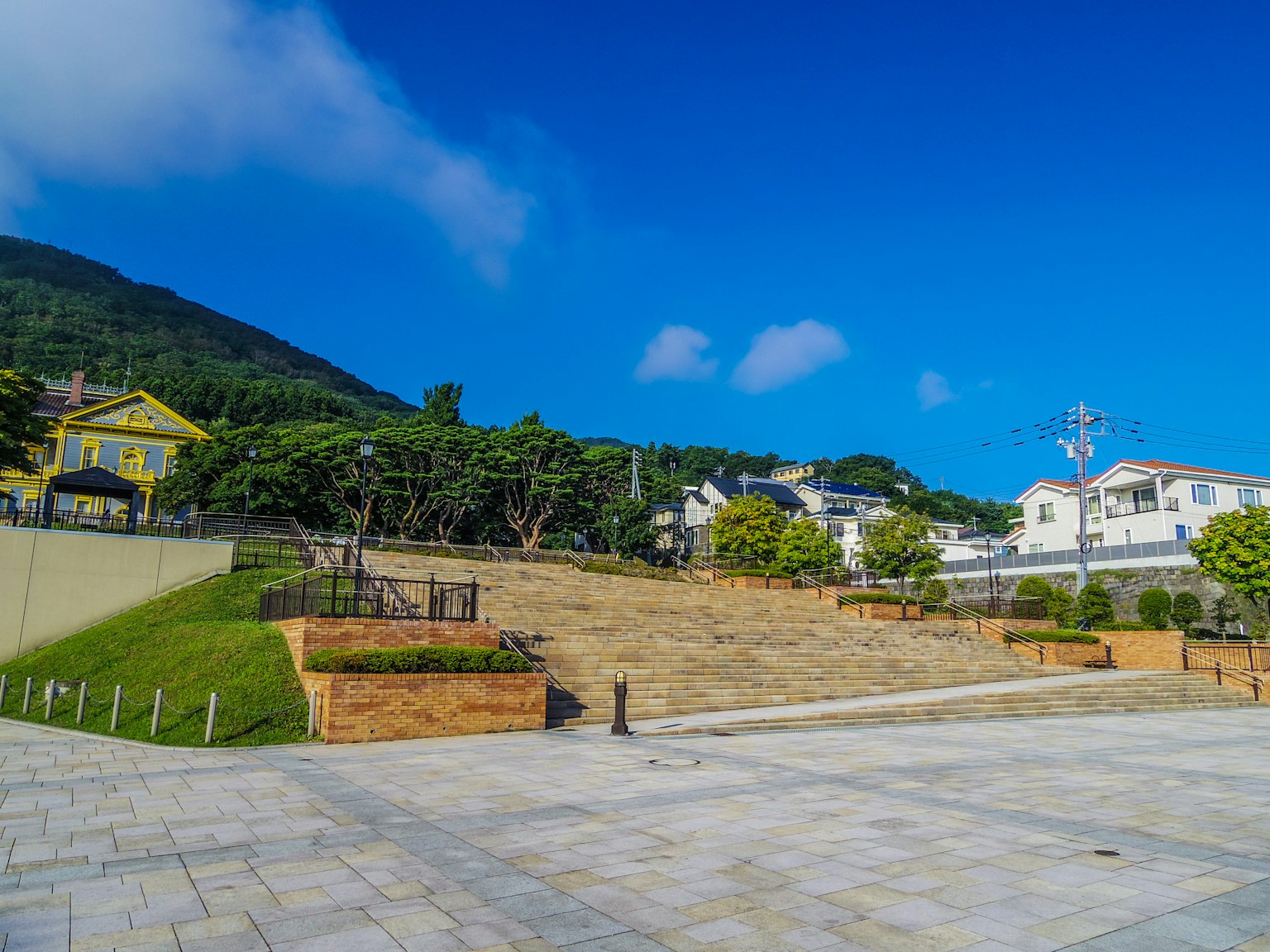 Un parque y una zona residencial bajo un cielo azul claro con vegetación paisajística y espacio abierto