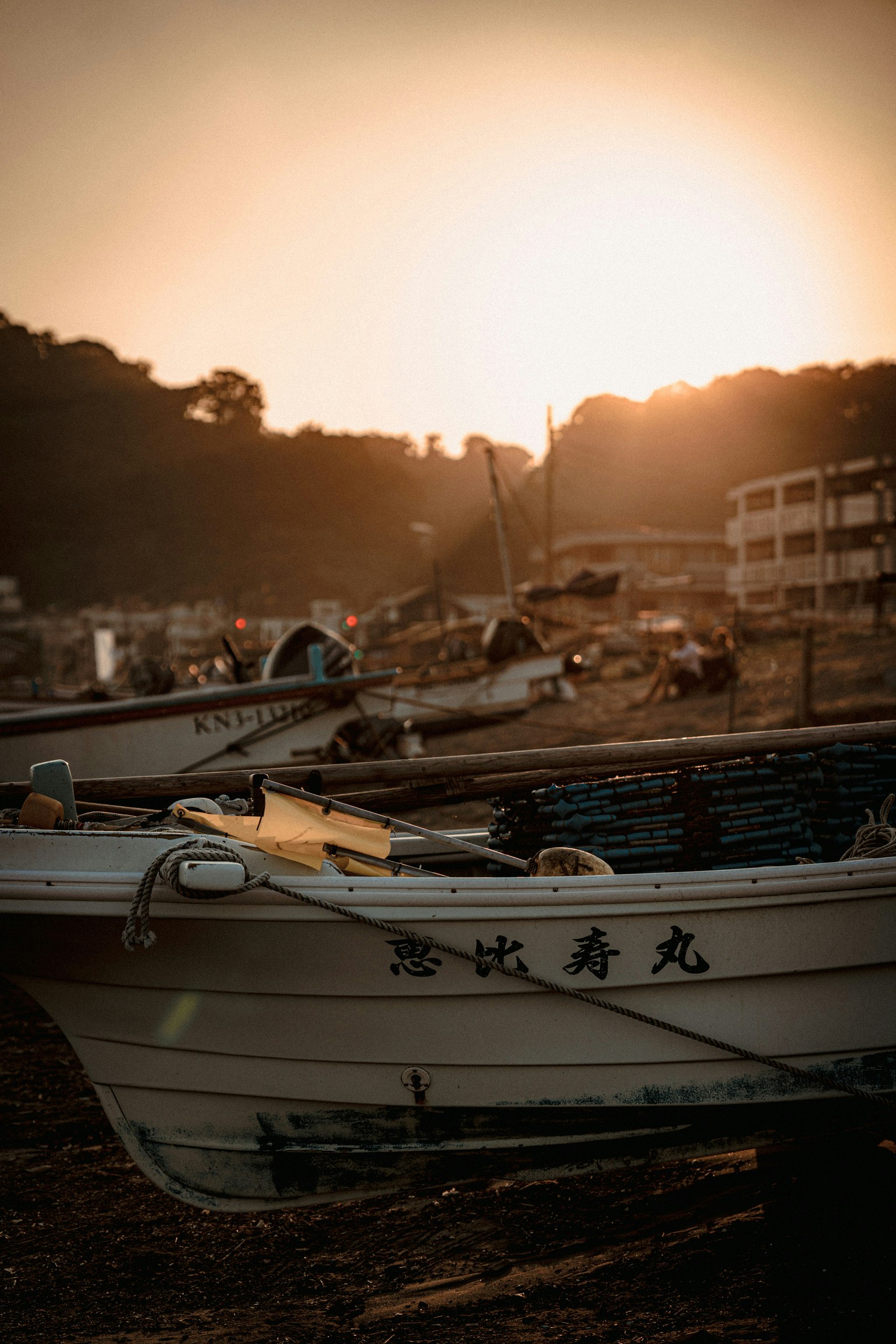 夕日に照らされた小舟と漁具のある港の岸辺