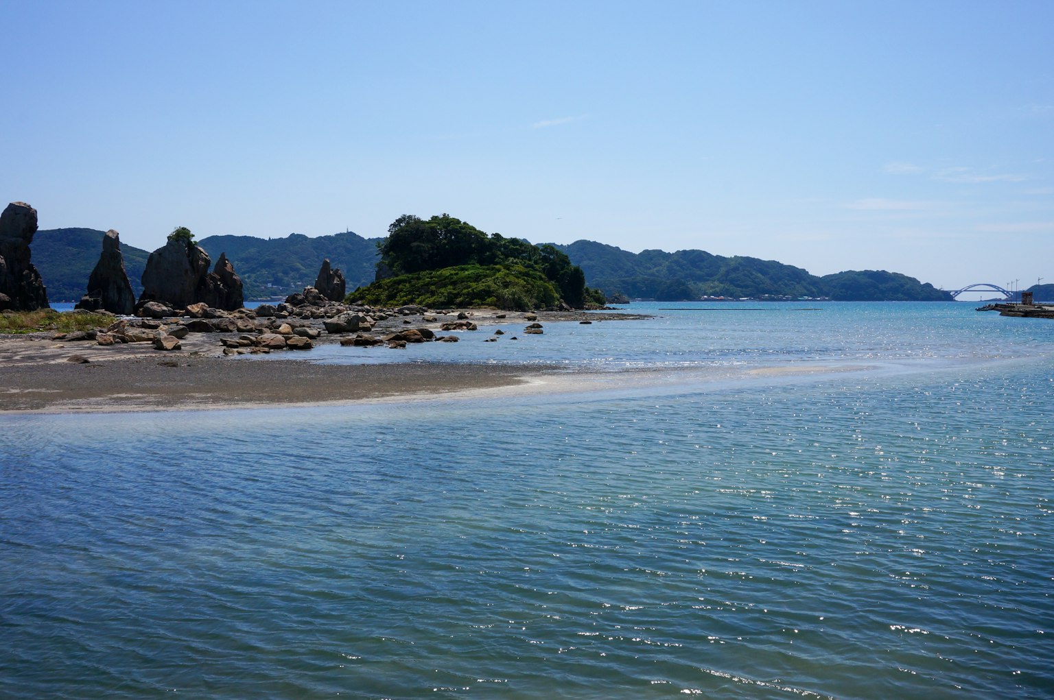 Beautiful landscape of blue sea with a small island and scattered rocks along the shore