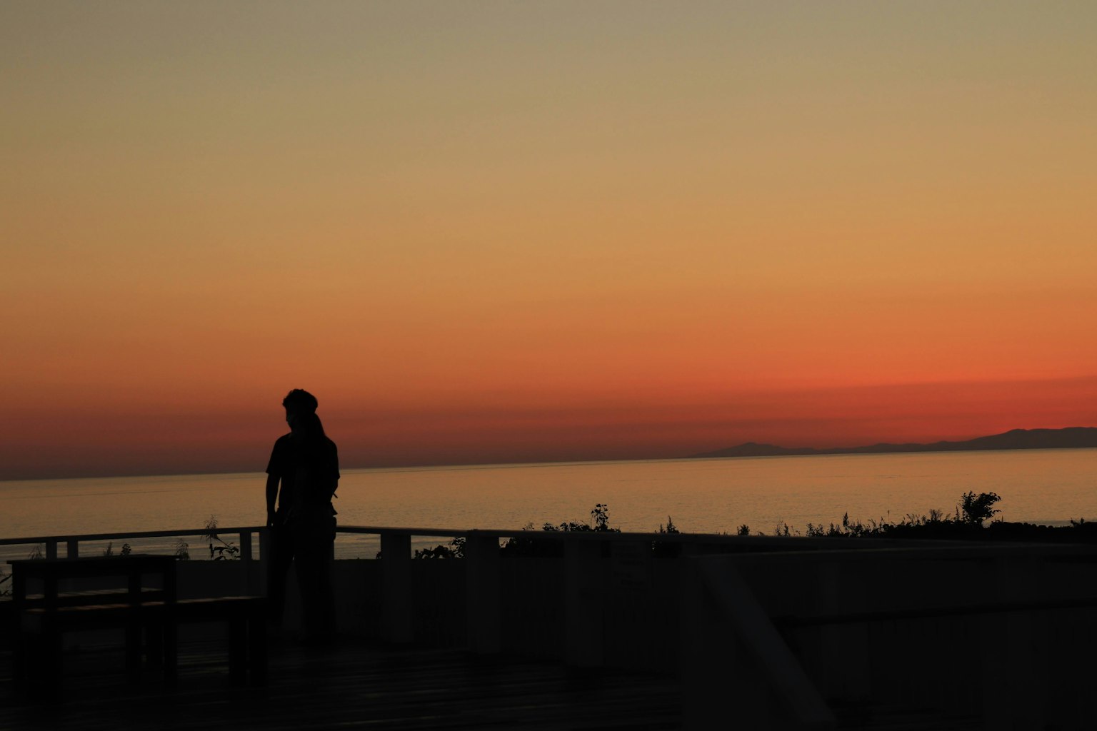 Silhouette di una persona che osserva il tramonto sull'oceano