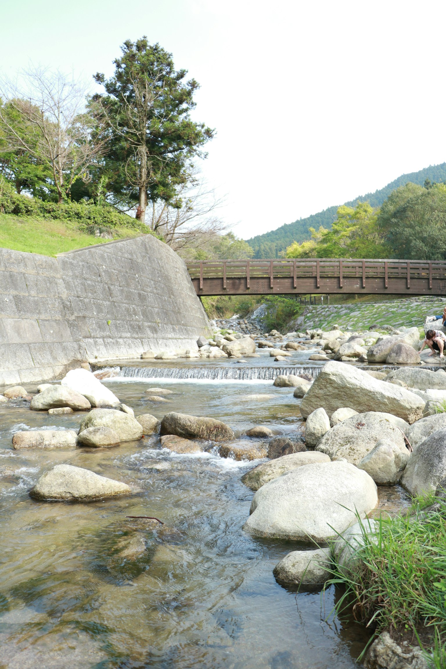 Pemandangan sungai dengan batu dan jembatan yang melintasi